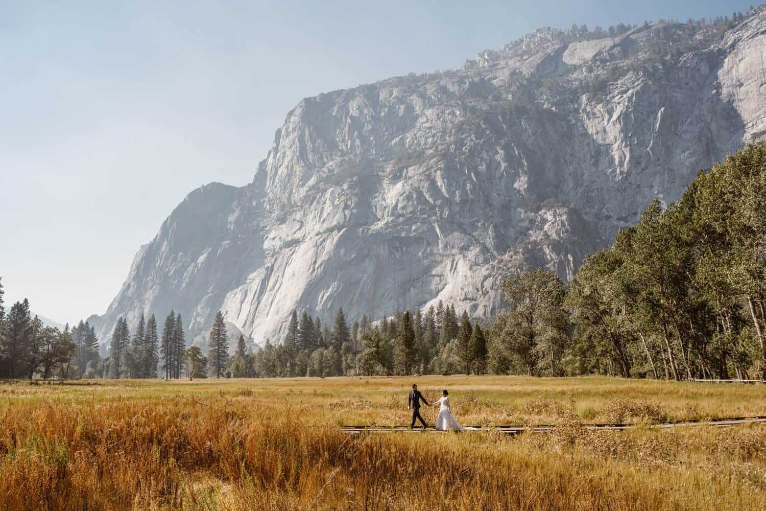 A couple walking across in a bridge in Yosemite during the fall.