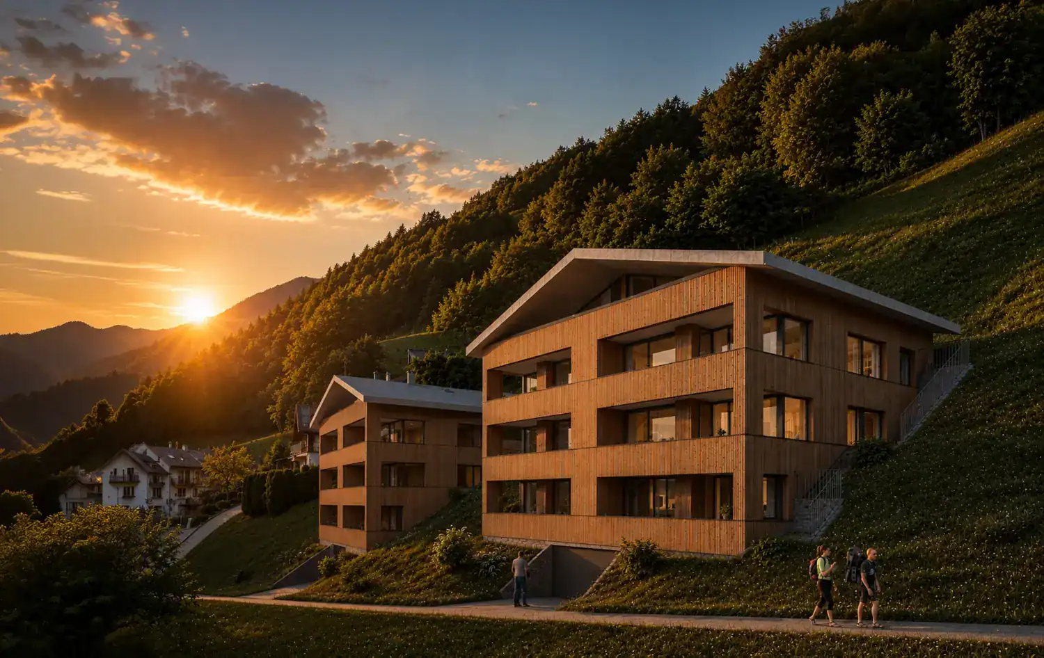 Außenansicht der modernen, holzverkleideten Silvretta Panorama Suites von UplandParcs an einem grünen Berghang bei Sonnenuntergang.
