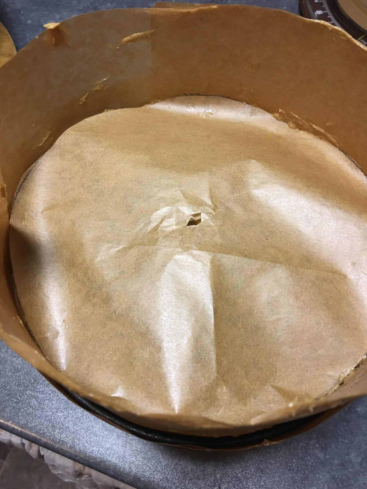 cake mixture in tin covered in double layer of greaseproof paper