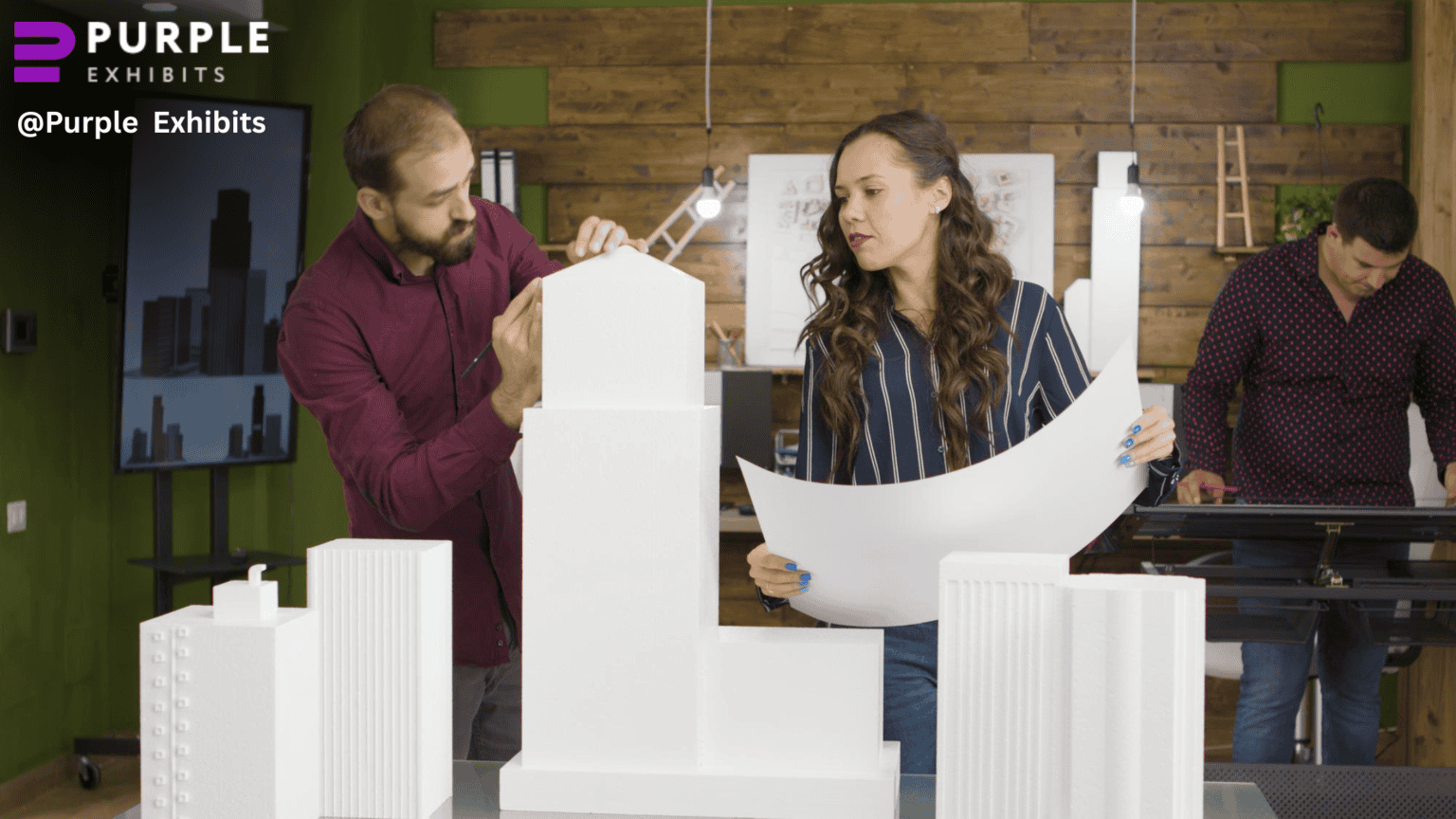 Exhibit designers collaborate around architectural models and blueprints, highlighting hands-on planning by a Chicago Display Company specializing in Chicago Exhibit Installation Services.