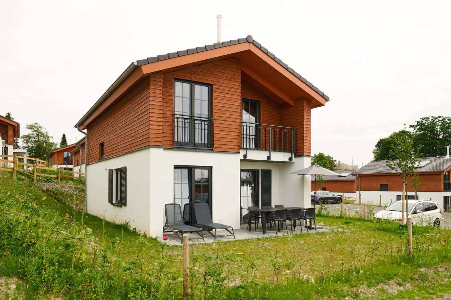 Freistehendes Ferienhaus im UplandParcs Winterberg mit Holzfassade, Balkon und Terrasse auf grüner Wiese
