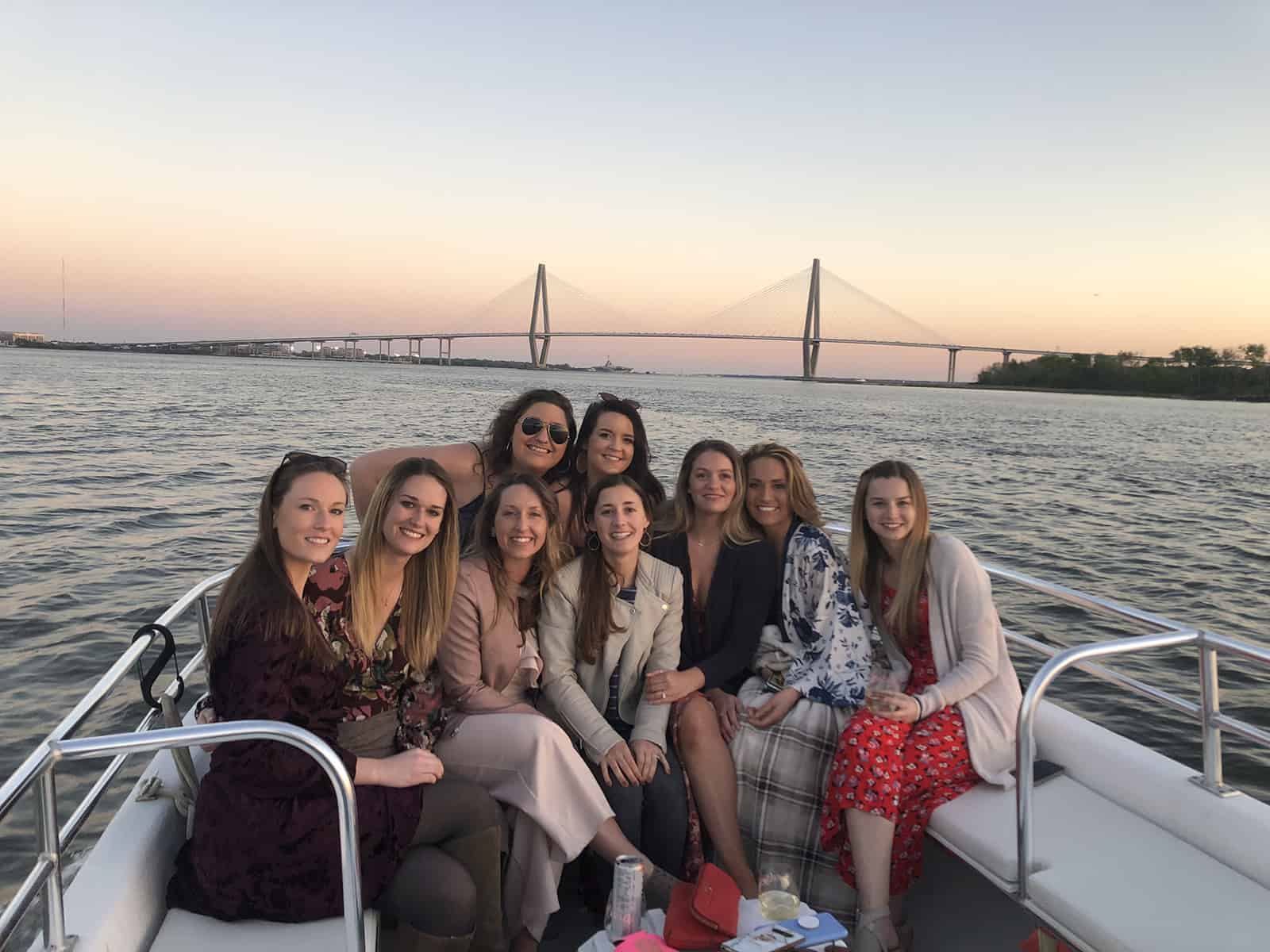 Group of women in front of sunset and bridge. Sunset cocktail cruise Charleston, SC