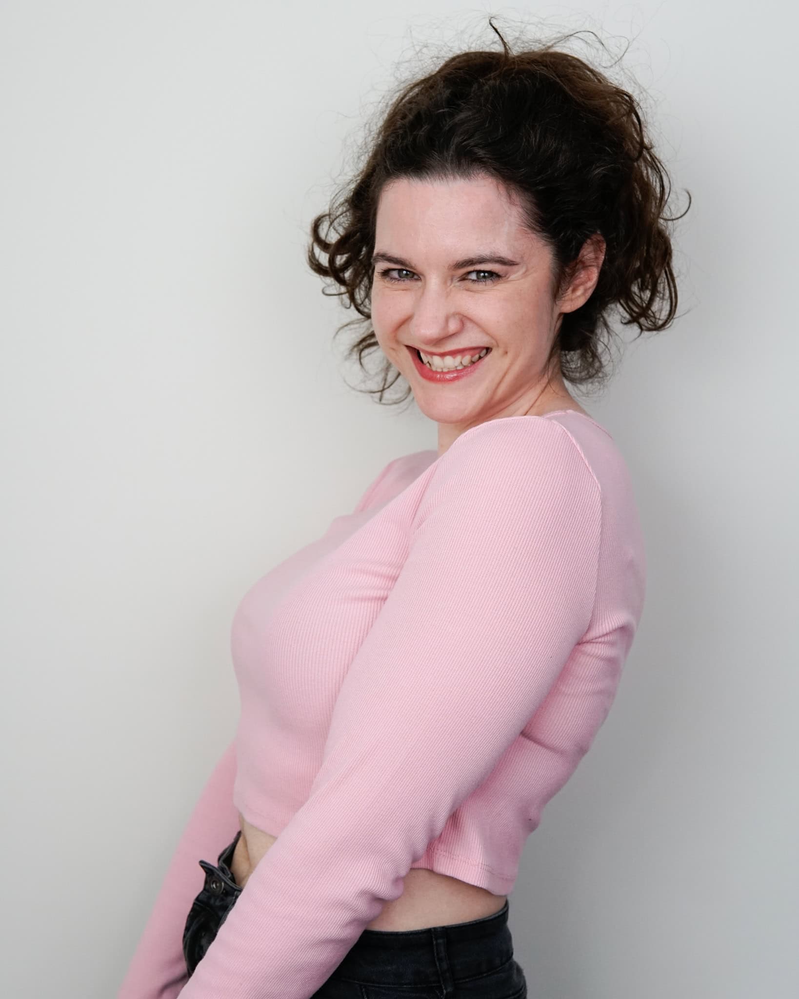 Australian woman voiceover artist Nina Nikolic smiles for the camera in pink shirt and bright smile