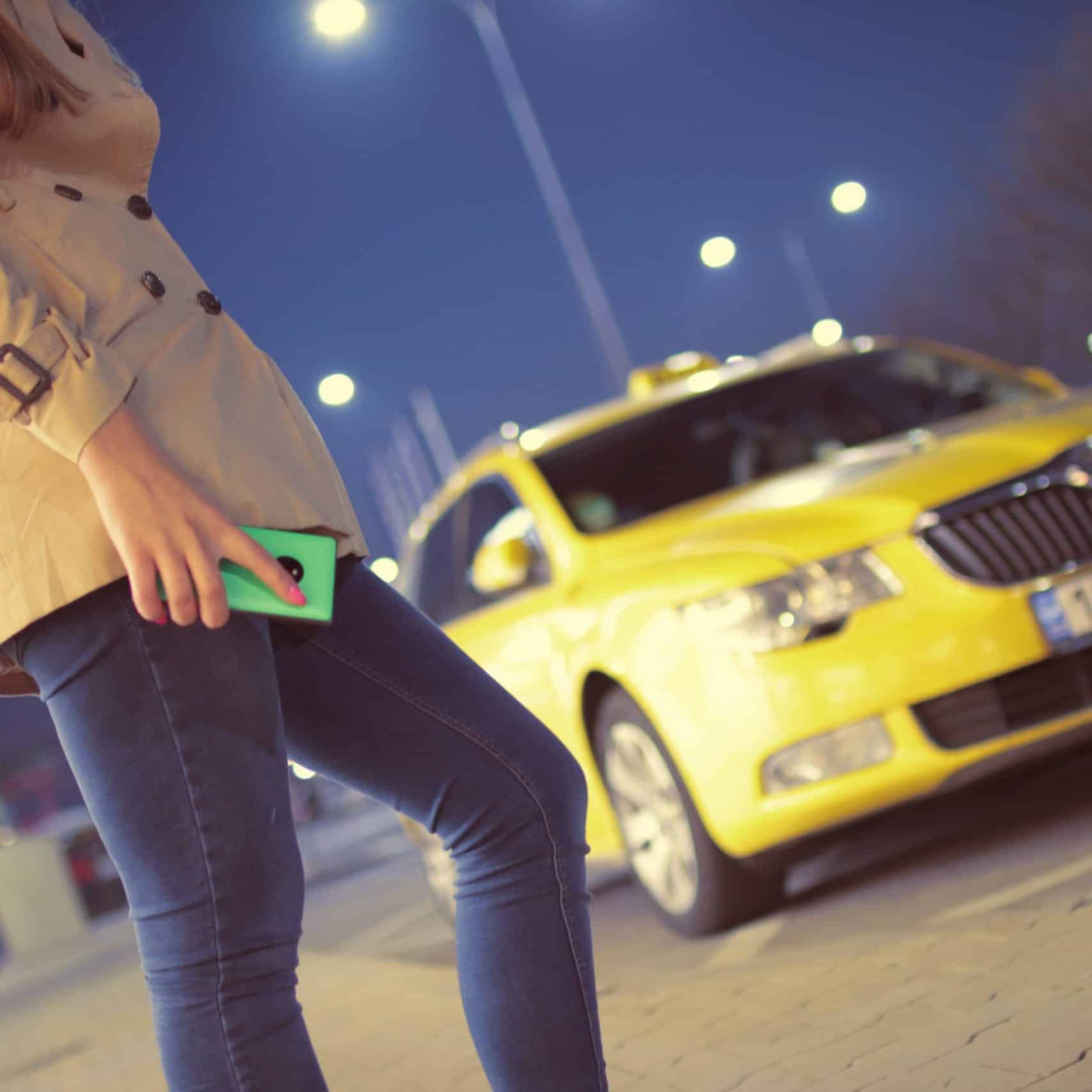 pexels-jéshoots-7405 Mujer con un telefono móvil junto a un taxi