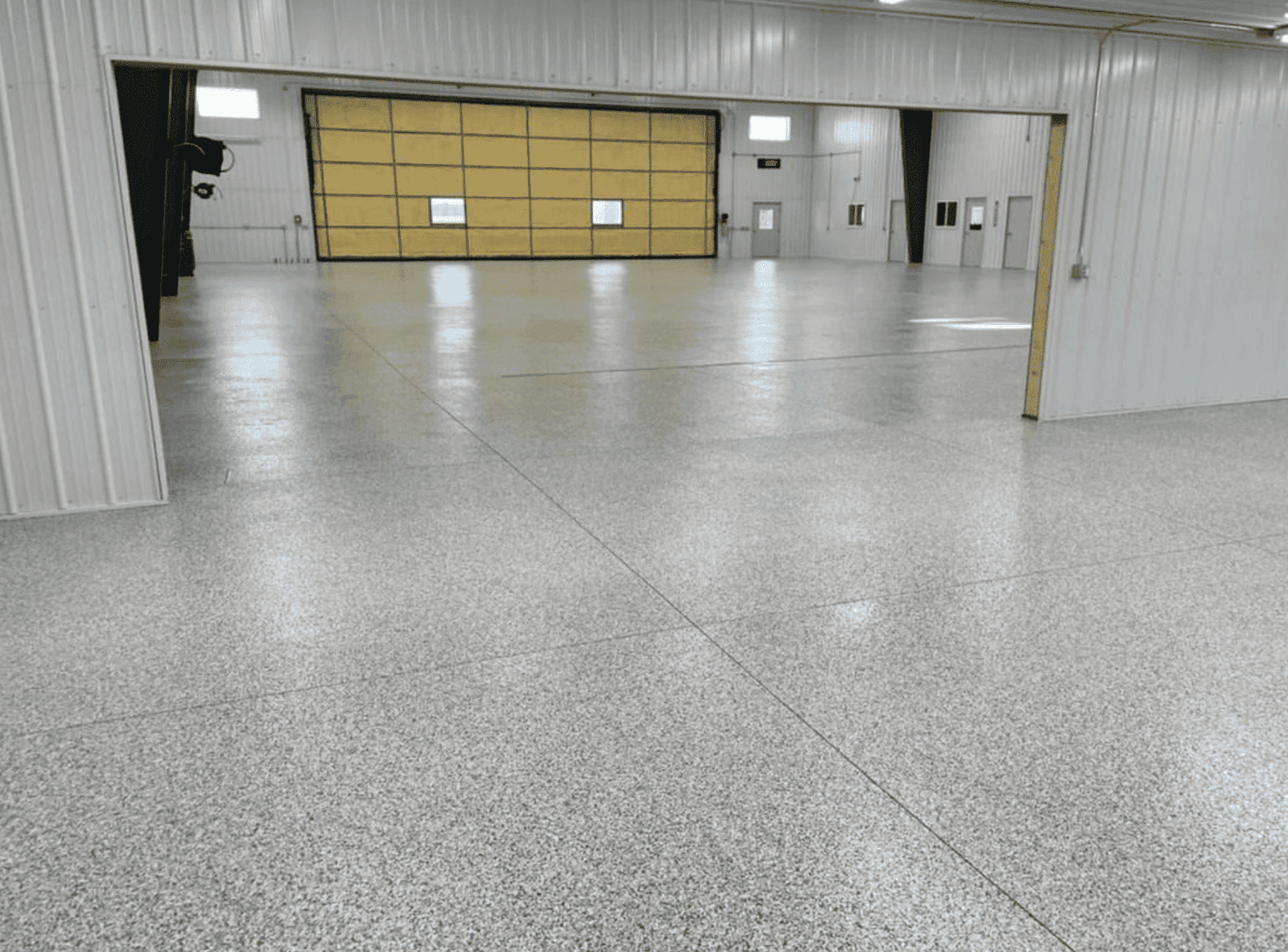 Spacious industrial warehouse with polished concrete floors and bright lighting, showcasing professional concrete finishing by top Minnesota contractors.