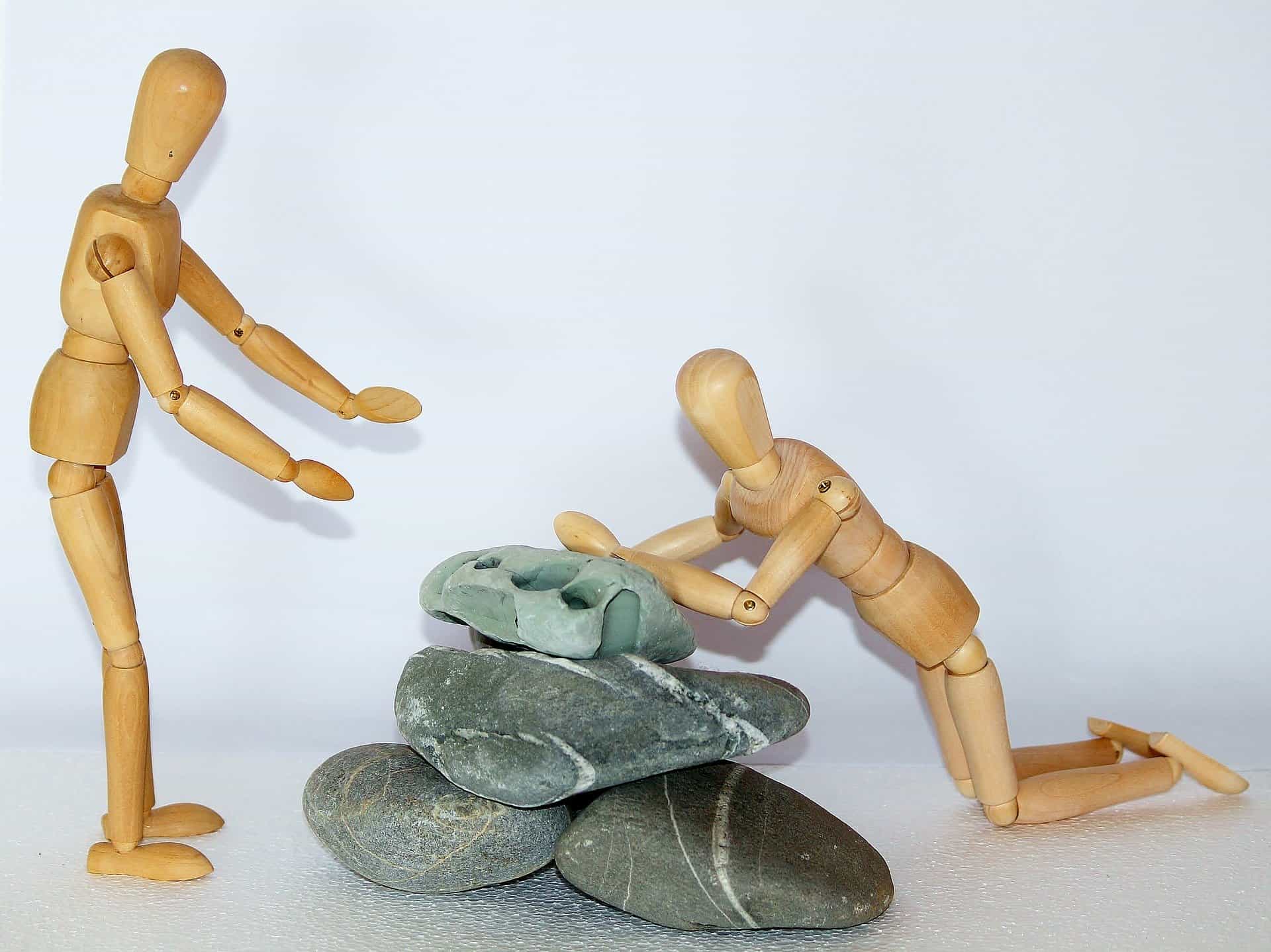 wooden figures pushing stones
