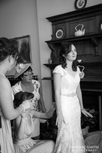 Hazels Mum and bridesmaids helping her with the dress