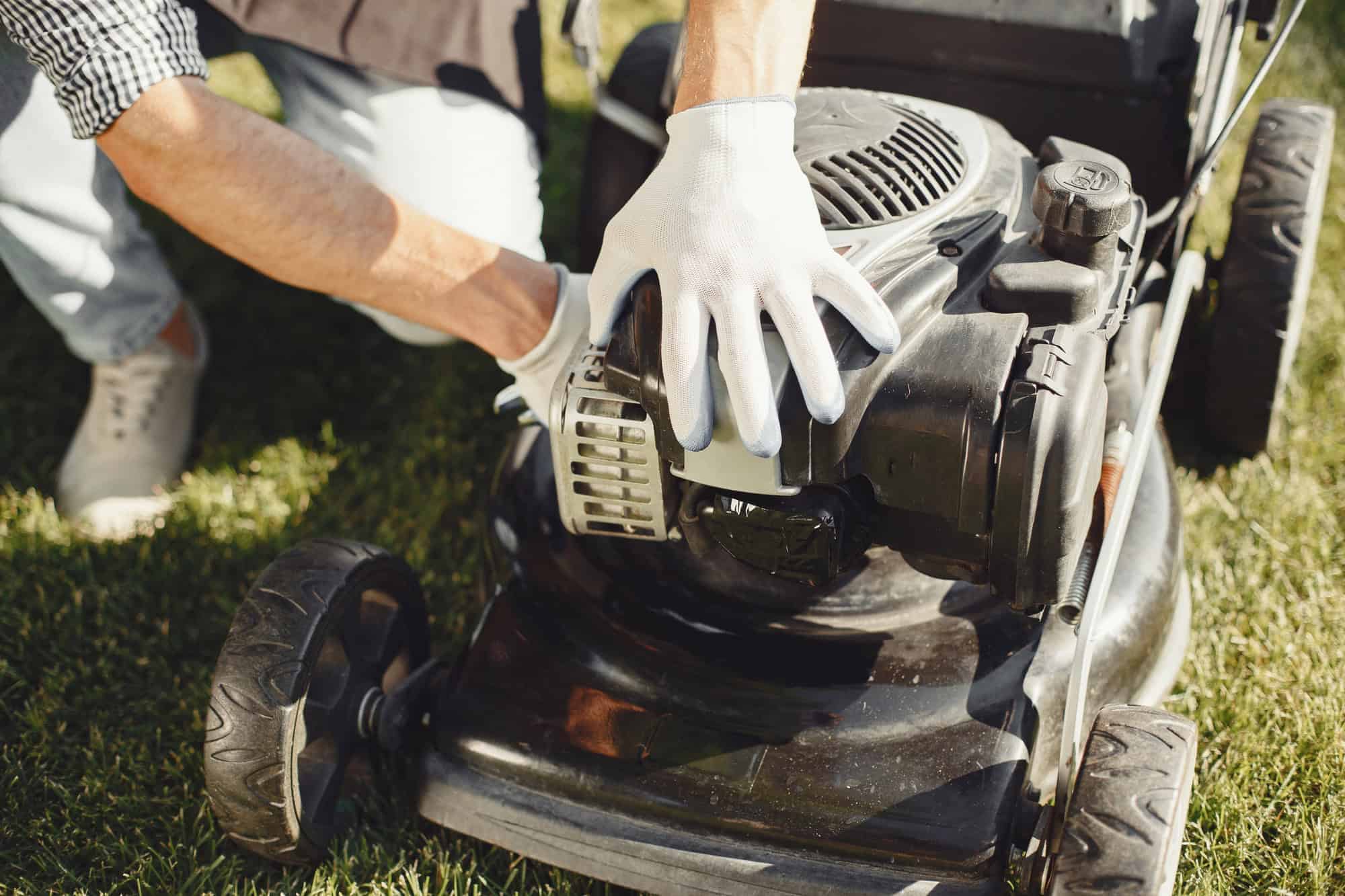 Man repairs lawnmover in a backyard
