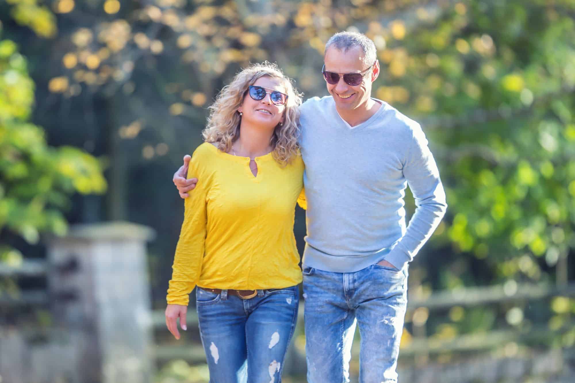 A happy middle-aged couple who finally found love a last, walking together, arm in arm, on a crisp autumn day.