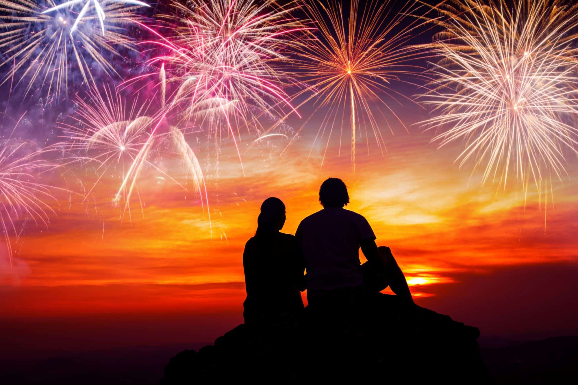 Silhouette of a couple watching fireworks in the sky who are no longer single on the Fourth of July.