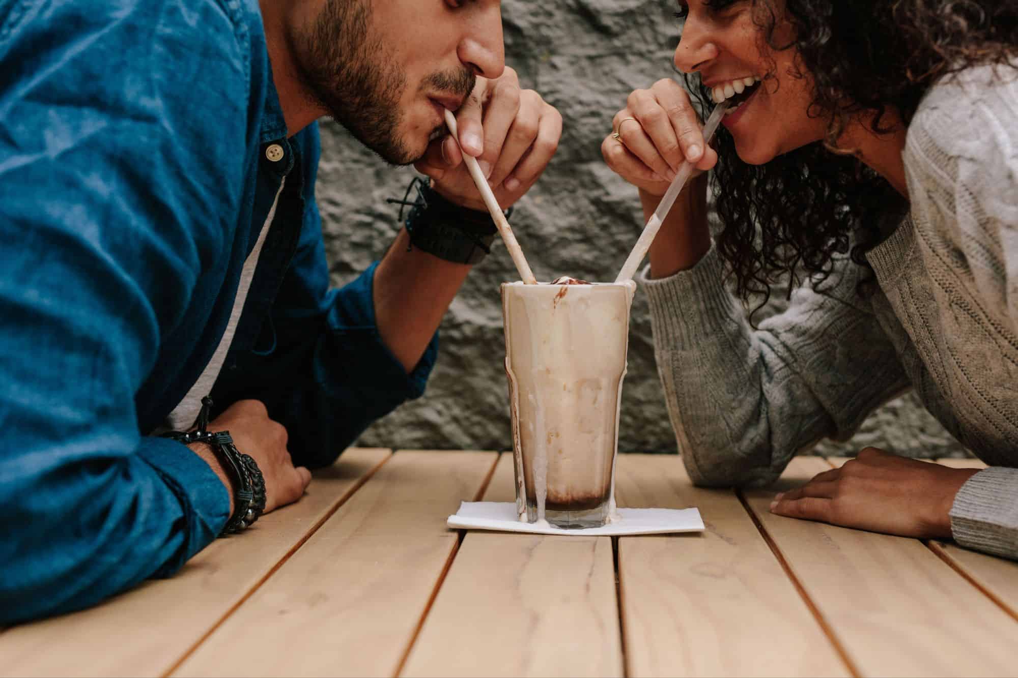 A man and a woman happily sharing a milkshake as they learnt of ind true love.