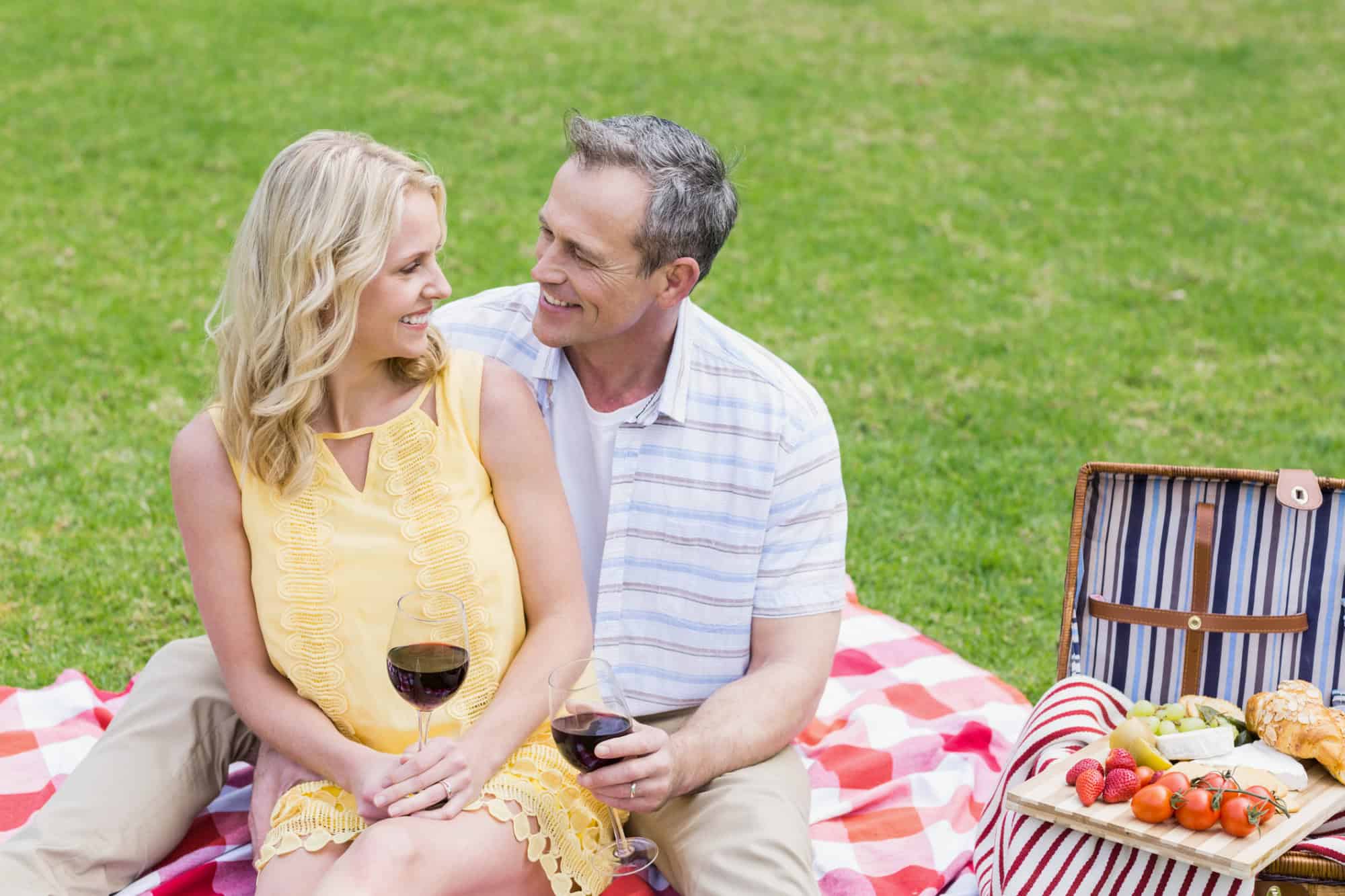 Man and woman cuddling while sharing a summer picnic.