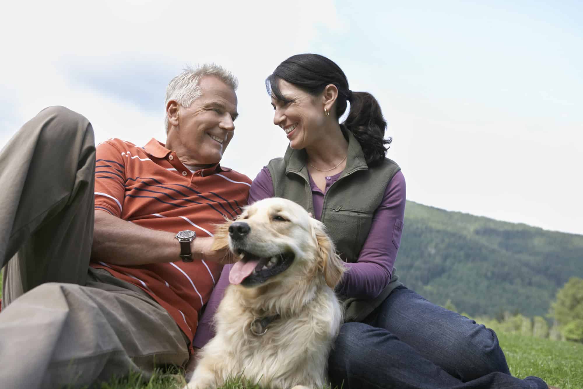 A couple sitting outside with their dog.