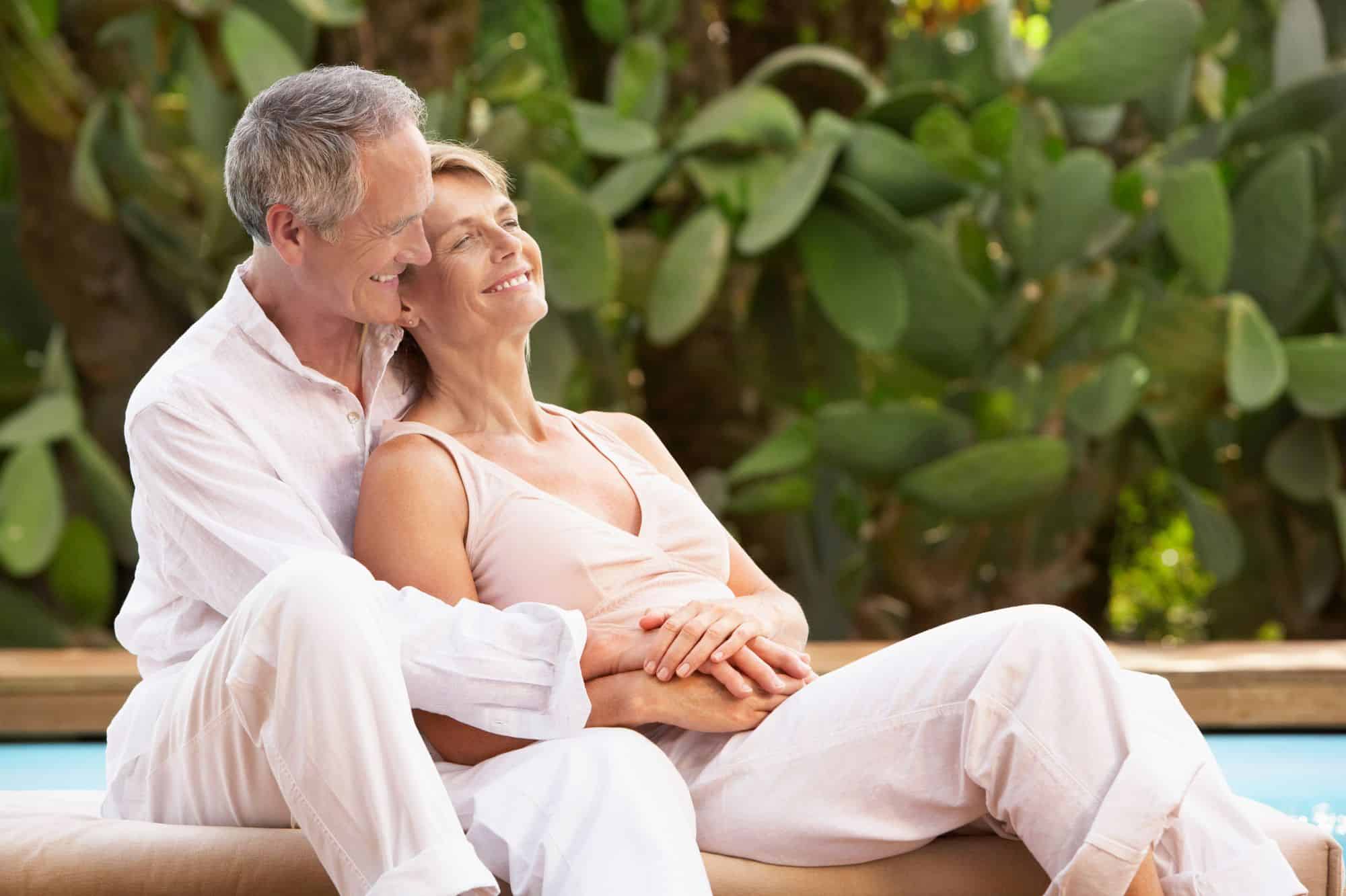 Mature couple who finally found long-lasting love blissfully holding each other outside by the pool.
