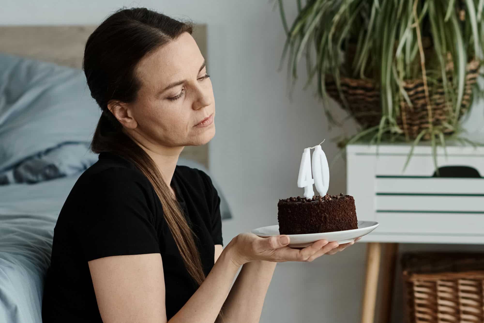 The new sleeping beauty- a woman who woke up at 40 and realized she's still single, sitting beside her bed holding a mini birthday cake.