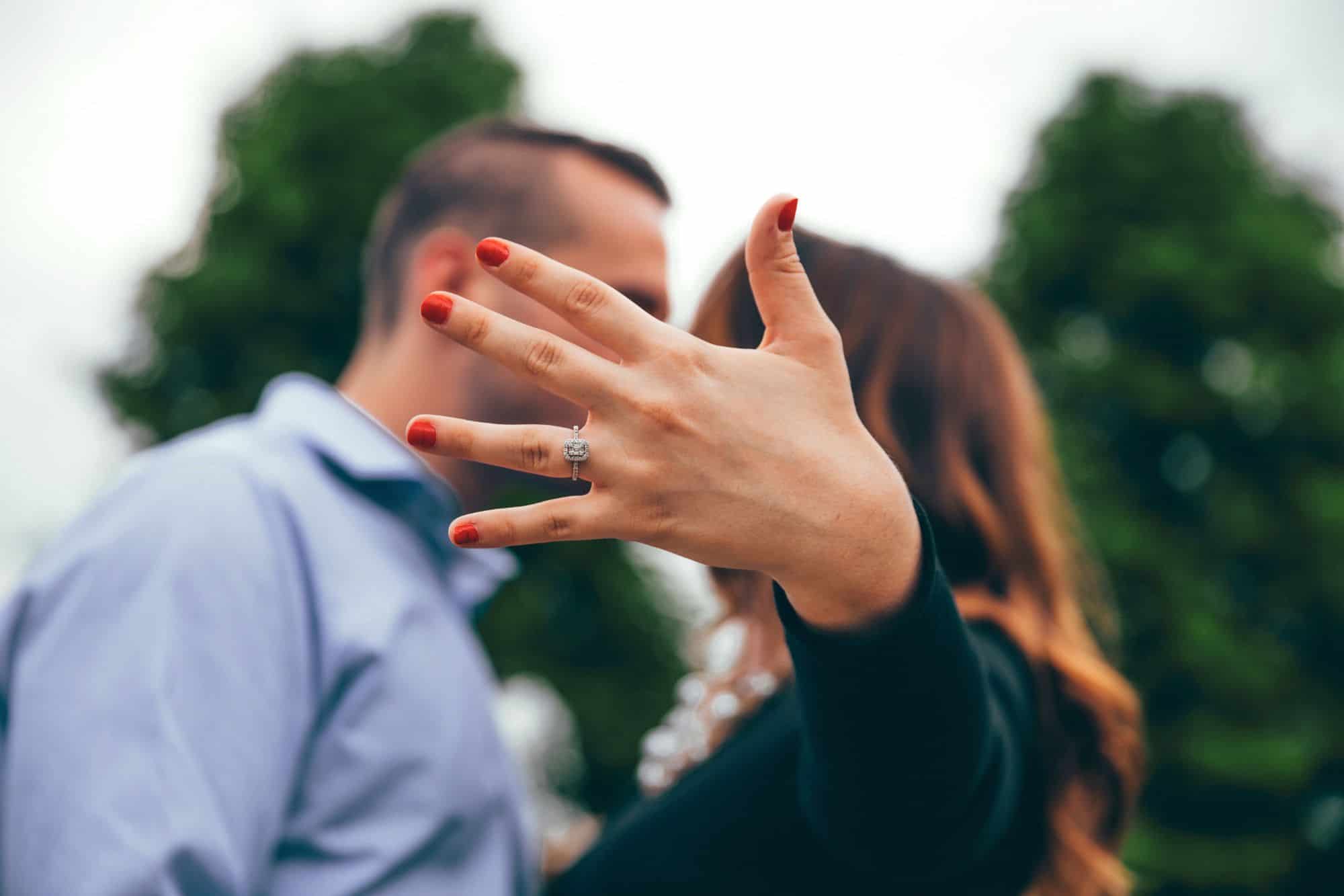 A kissing couple, who understood that dating to marry is different than just dating, showing off the engagement ring on her finger!