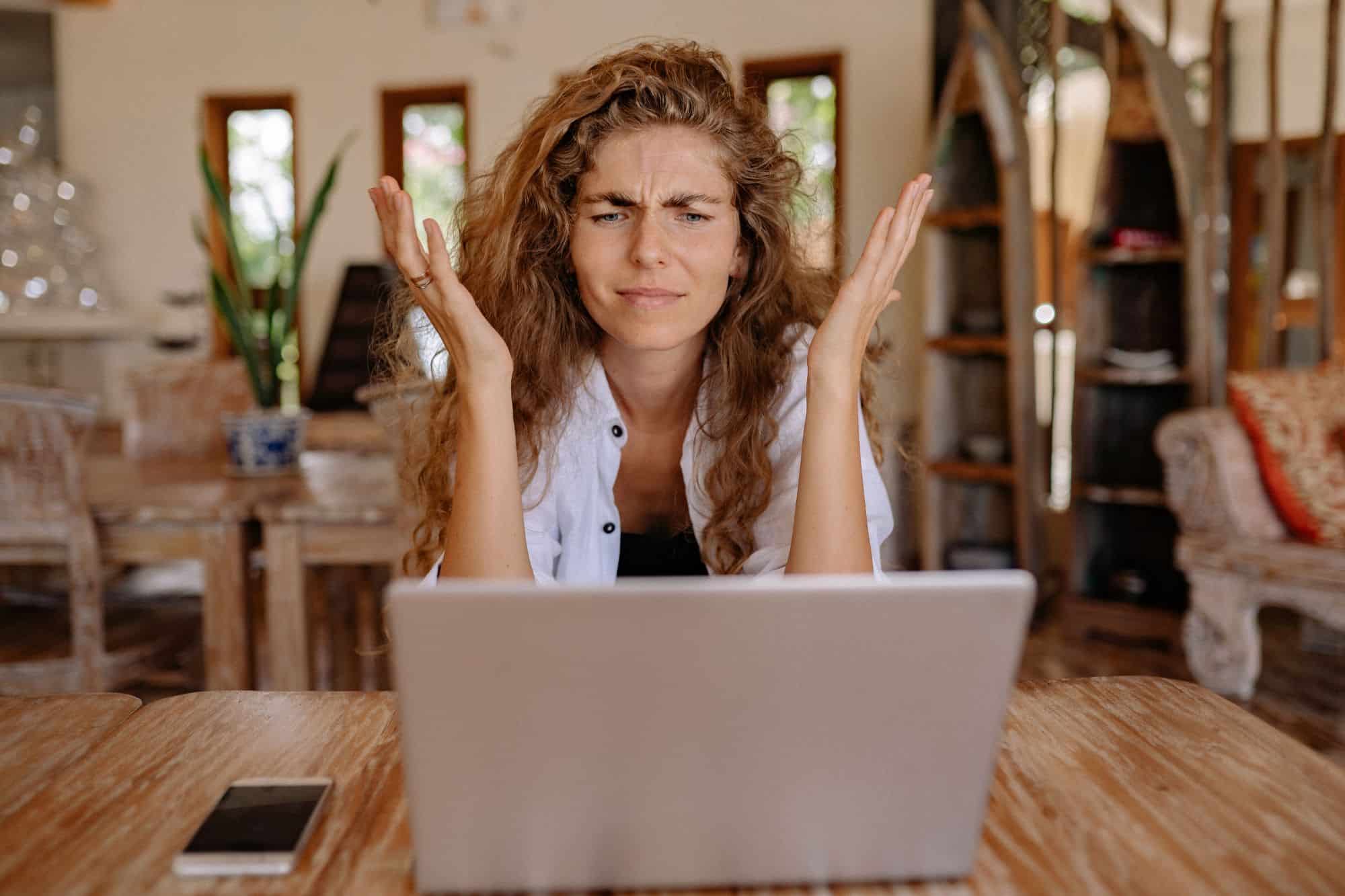 A woman who is frustrated with dating shakes her hands at her computer.