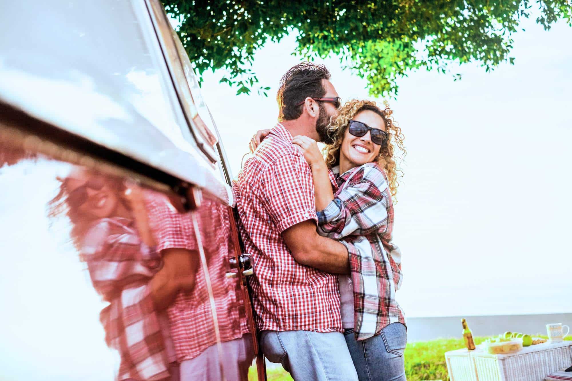 Happy couple who share similar relationship values, cuddling on a camping trip.