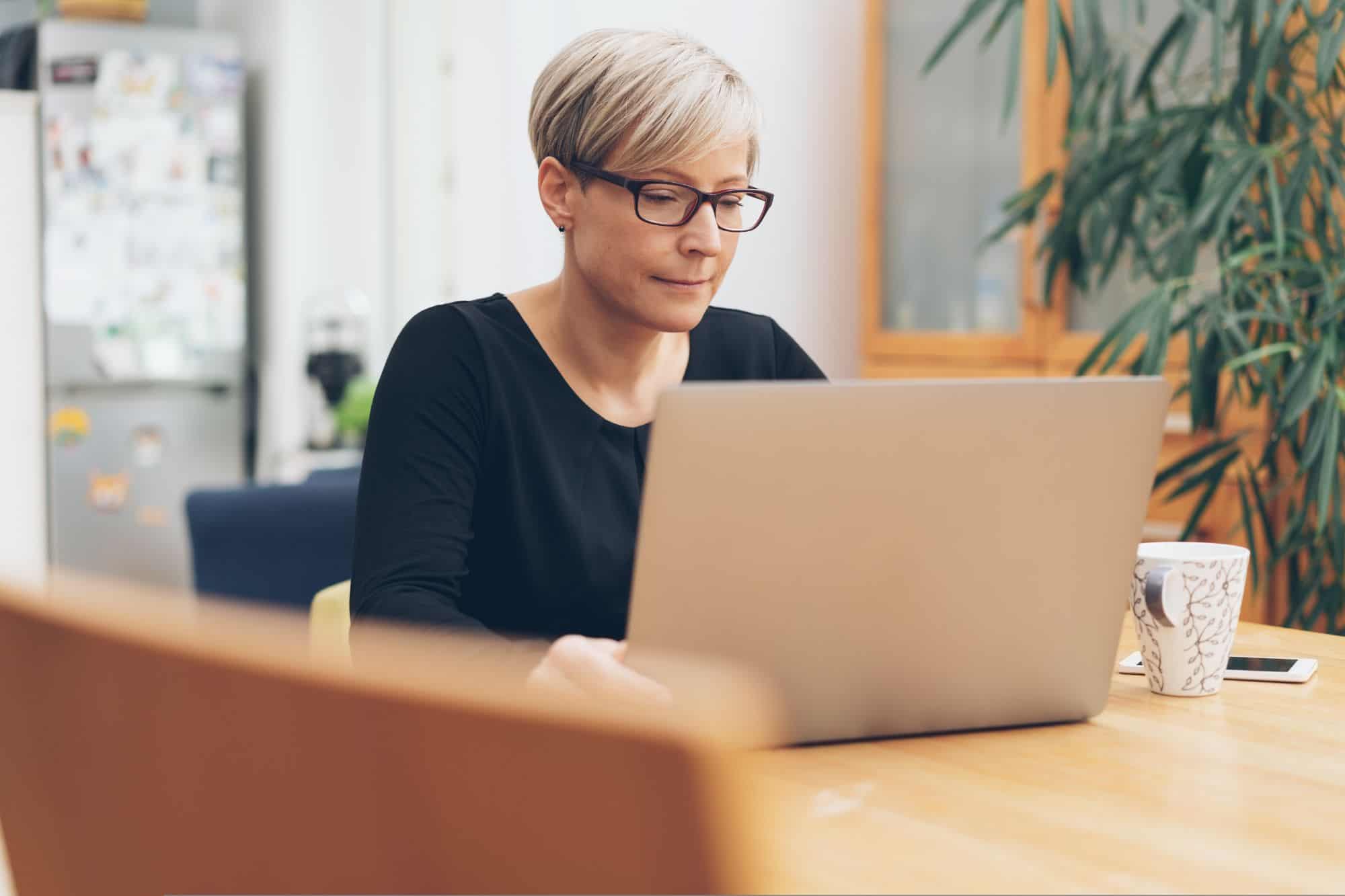 Woman on her laptop, messaging an online dating match and wondering "how long is too long to keep messaging before finally meeting?".