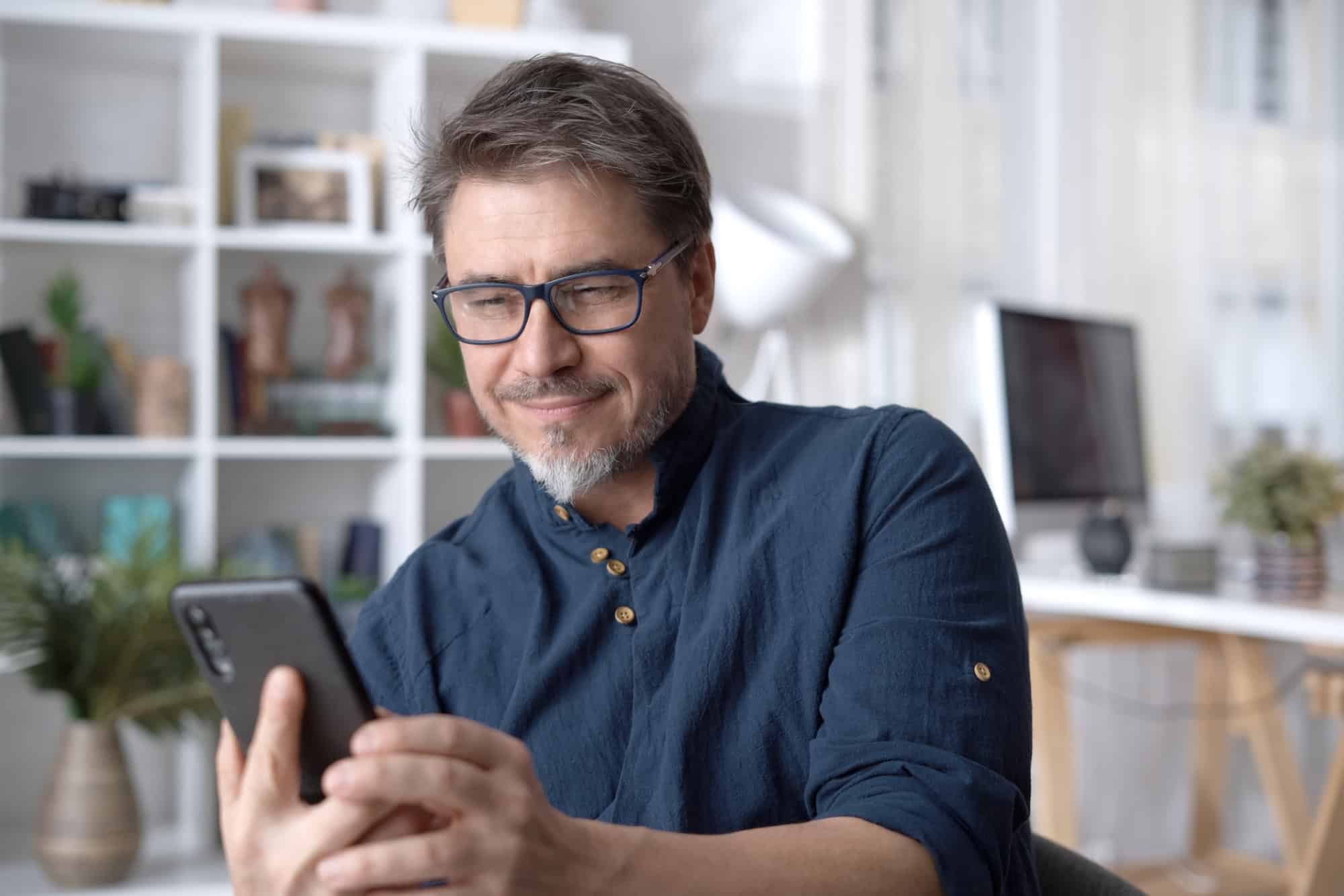 Man looking at a dating app on his phone and wondering if he should make the first move.