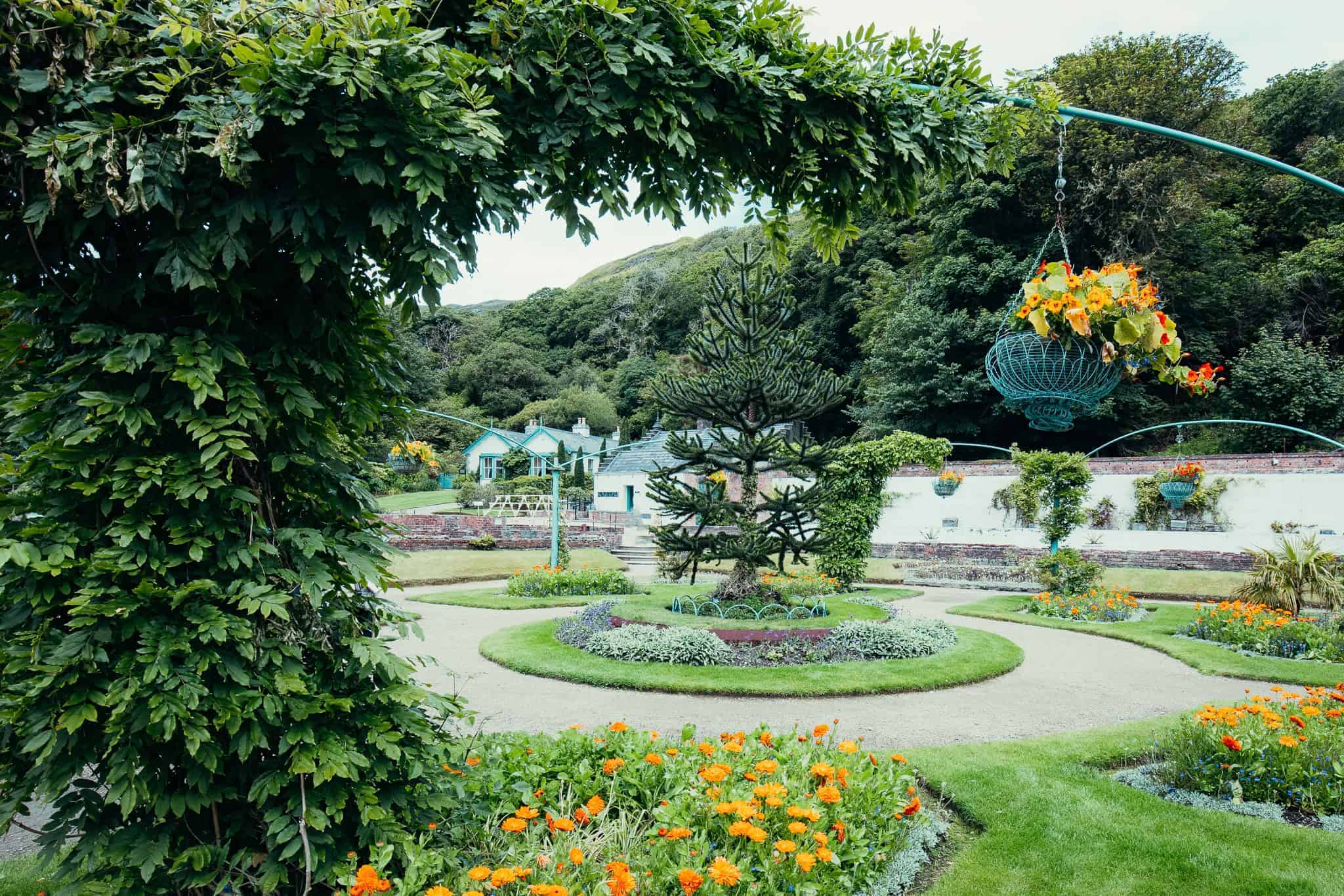 A beautifully landscaped garden at Kylemore Abbey, featuring vibrant flowers, manicured lawns, and decorative arches.