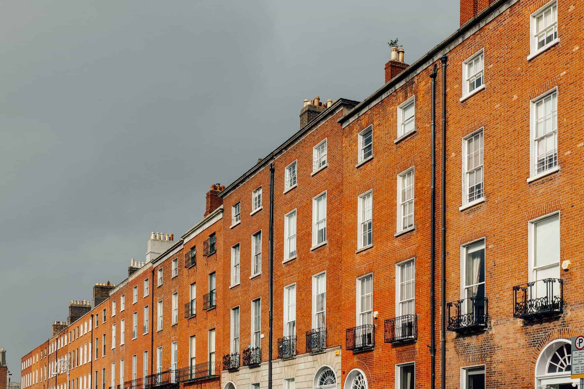 classic Georgian buildings in Dublin with red brick facades and tall windows, framed under an overcast sky.