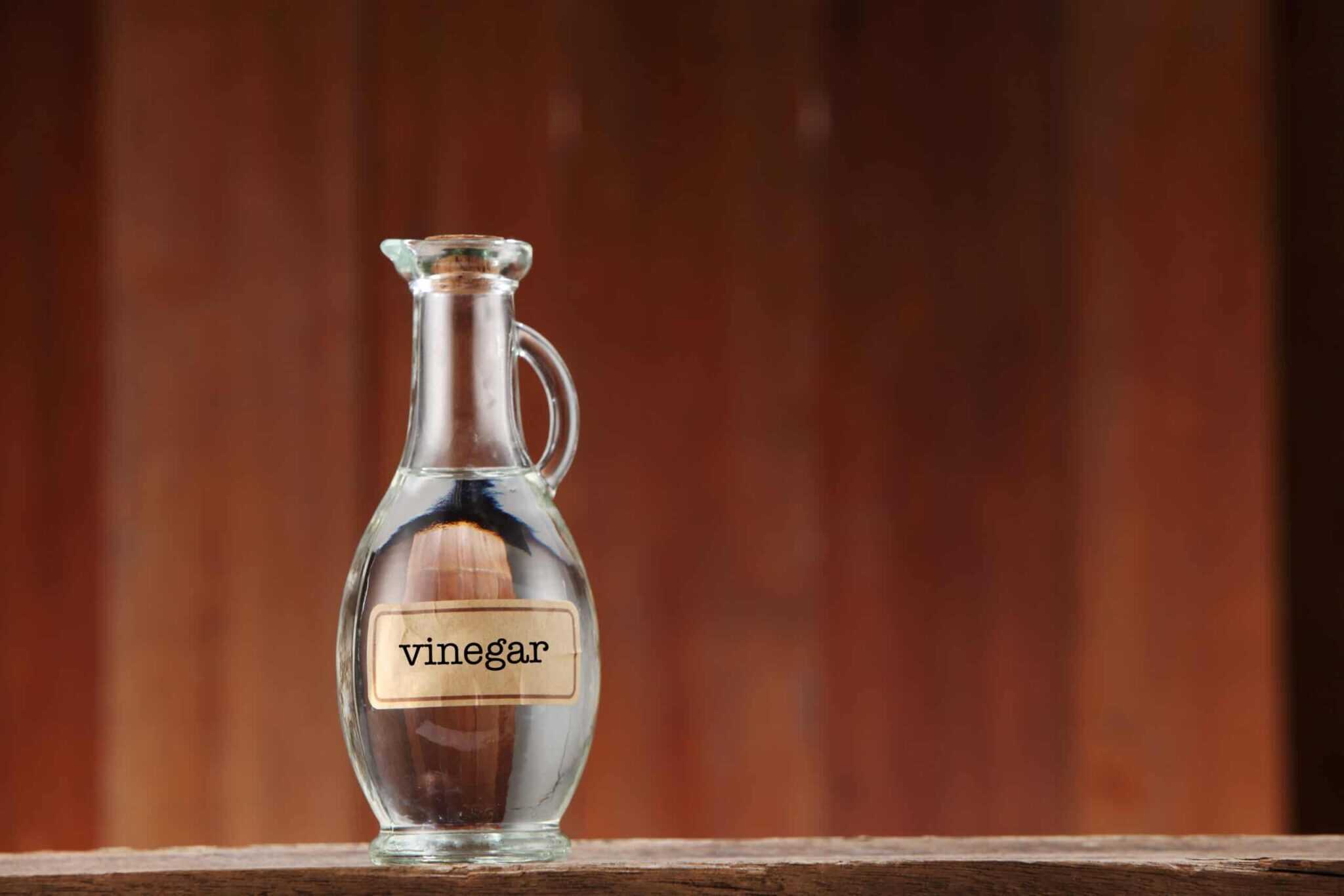 Close up of glass vase of vinegar against brown background
