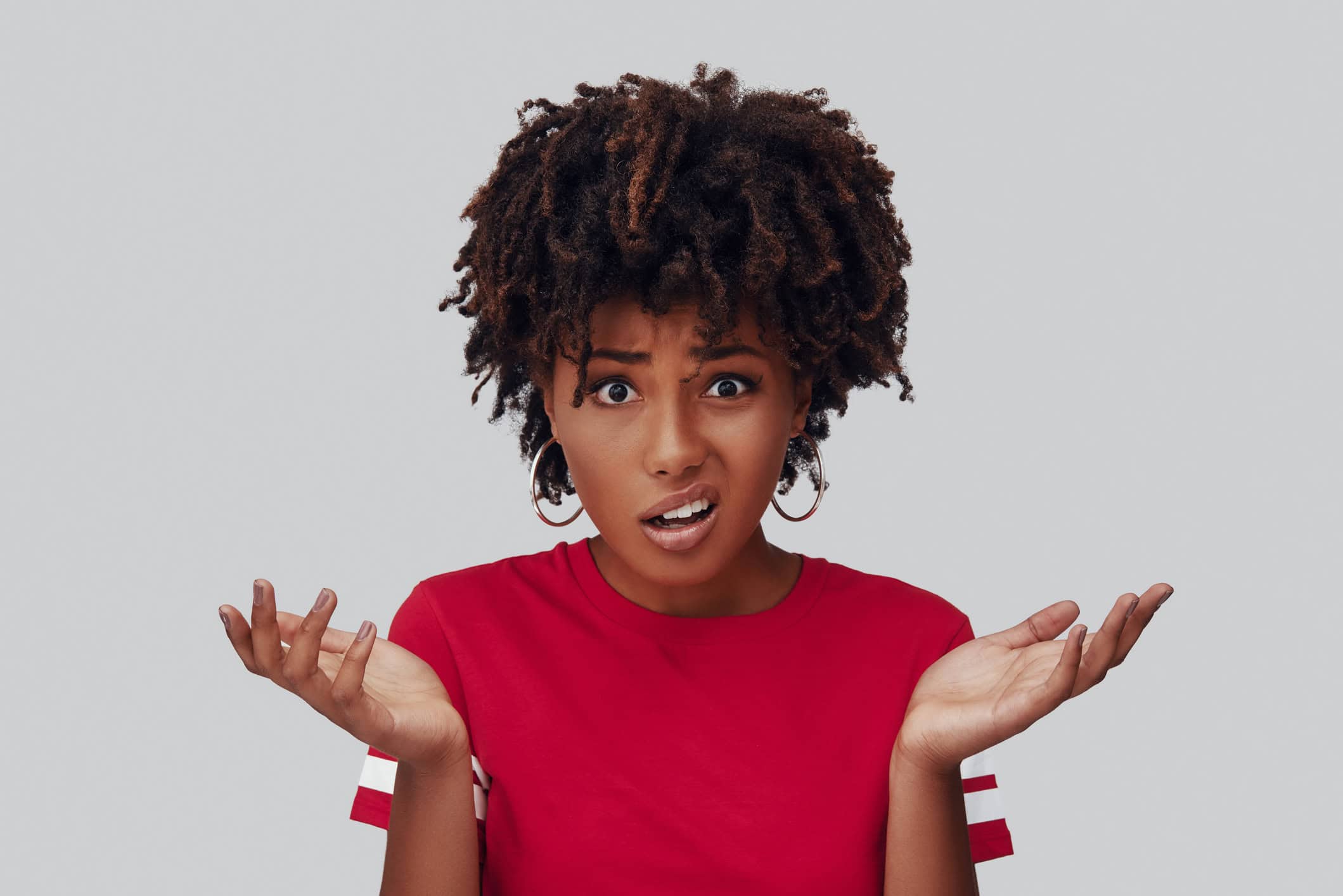 Woman with a frustrated expression holding her hands up and shrugging her shoulders.