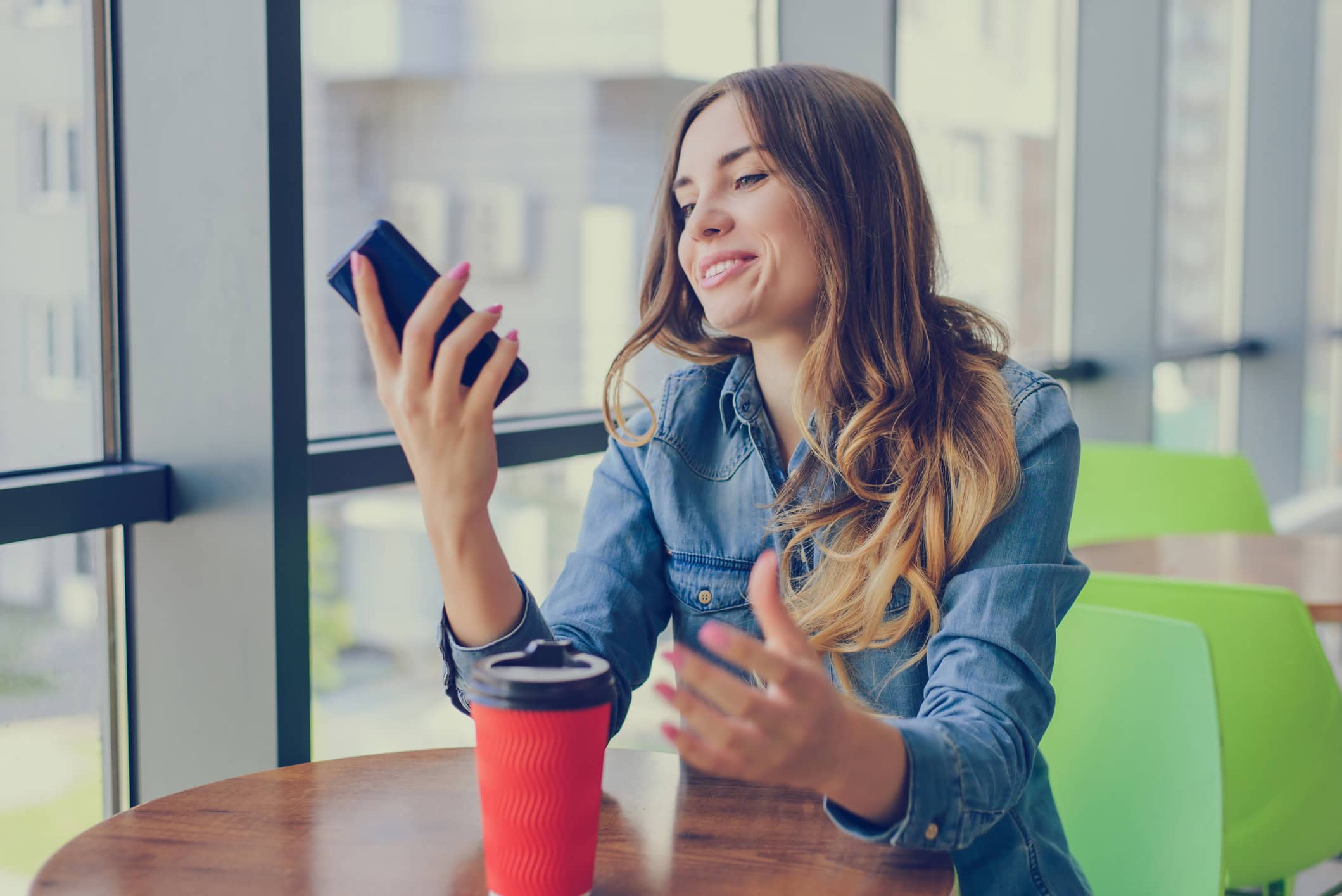 Woman sitting at a table looking at her online dating app.
