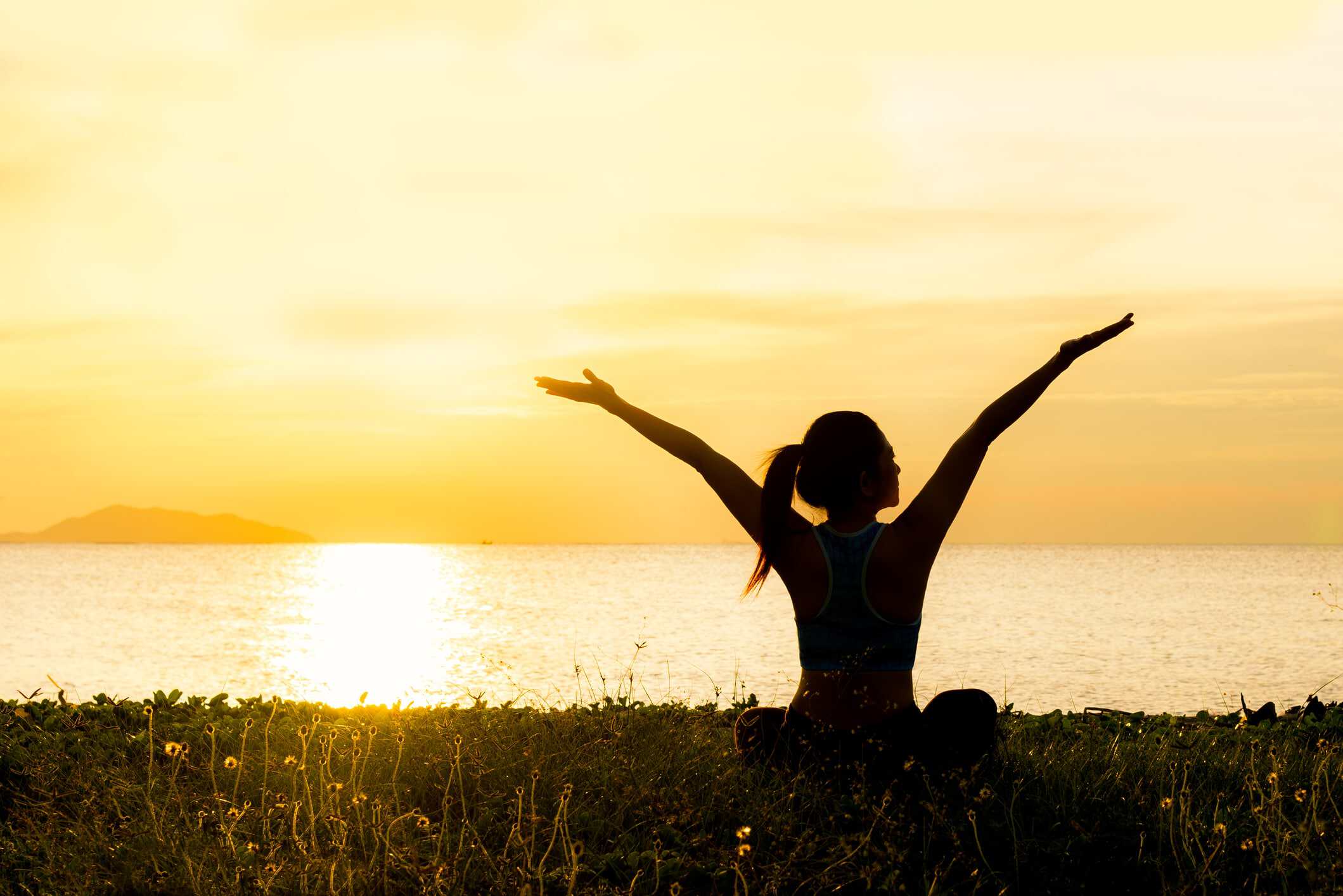 Woman meditating at sunrise, speaking affirmations for finding love over herself.