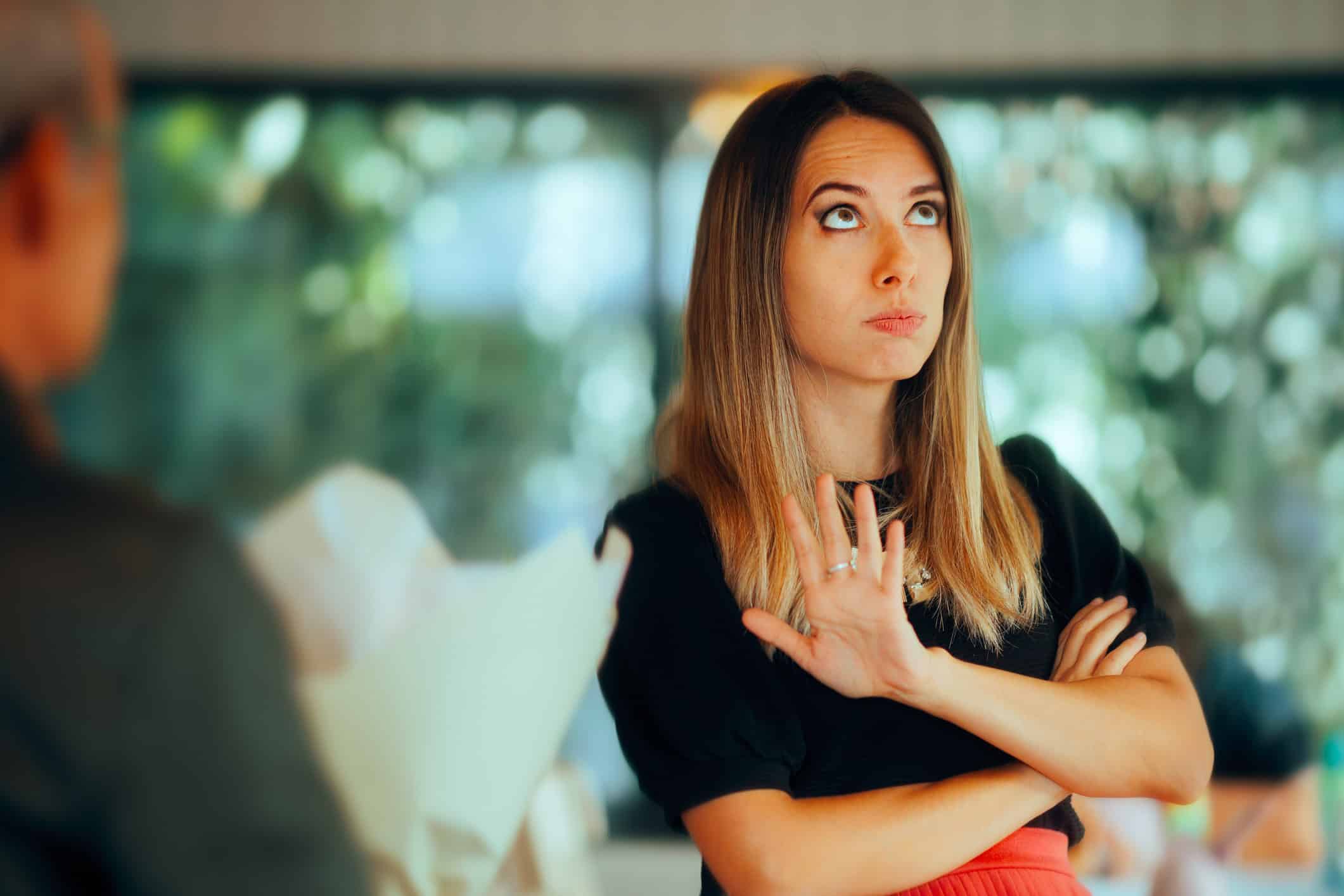 Irritated woman remembering to be careful who you date as she puts up her hand to keep her date away.