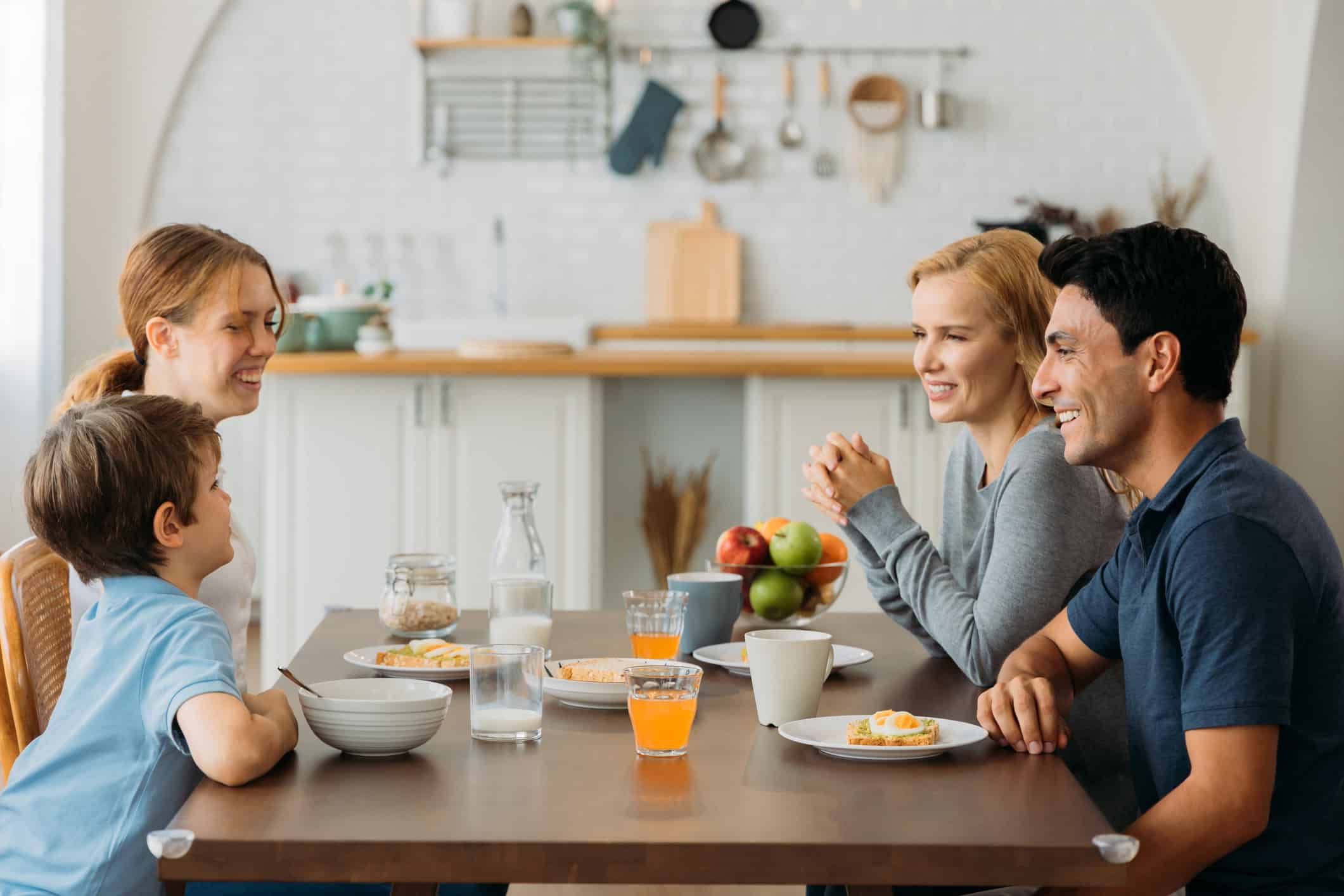 Man dating someone with children sitting at table smiling and enjoying a meal with the woman and her 2 kids.