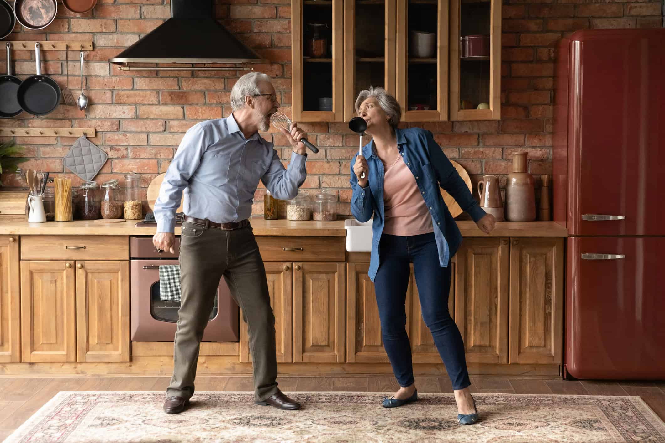 Happy middle-age couple singing together in the kitchen, about the top qualities to look for when choosing your life partner.