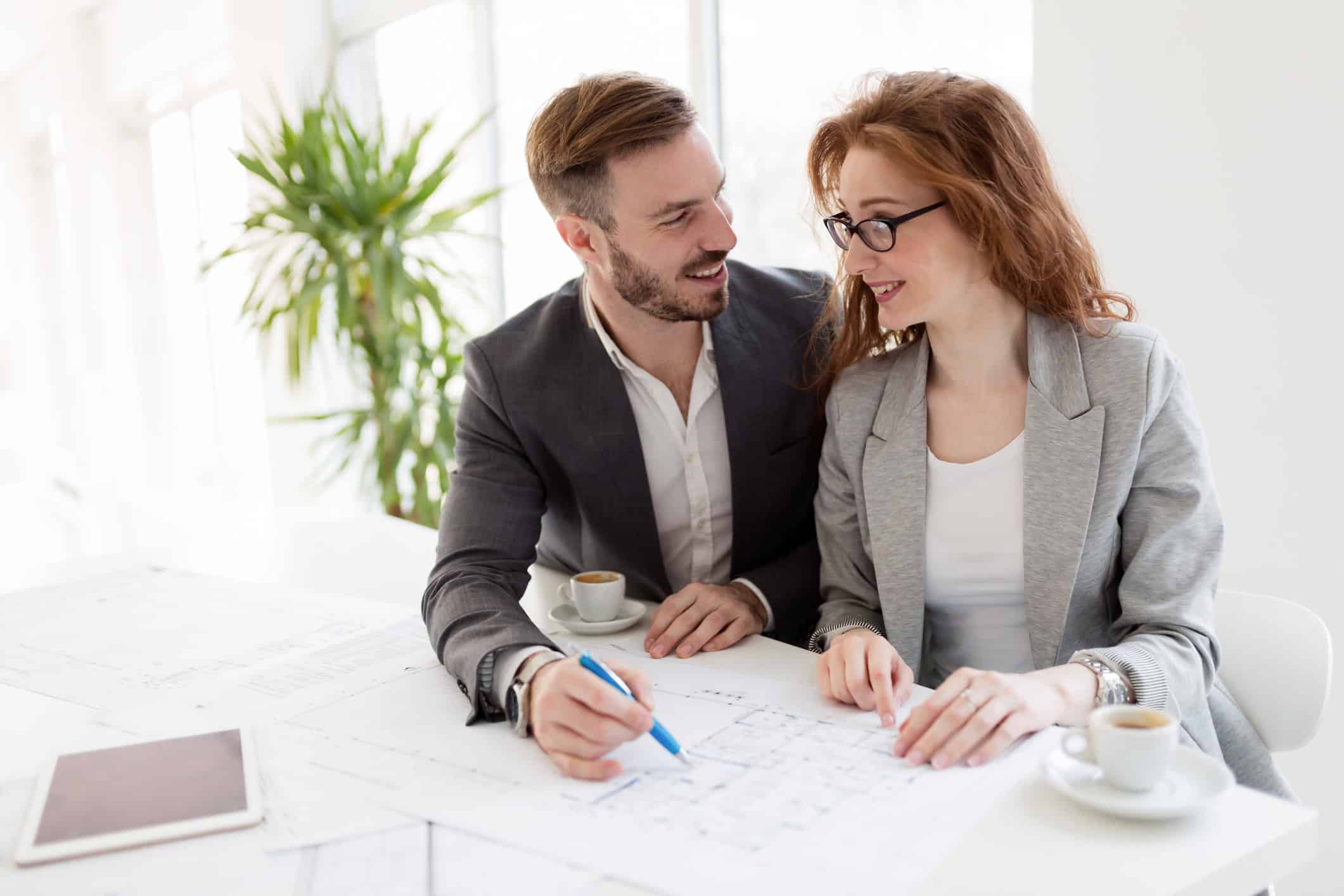 Male & female coworkers sitting close and flirting with each other as they begin a workplace romance.