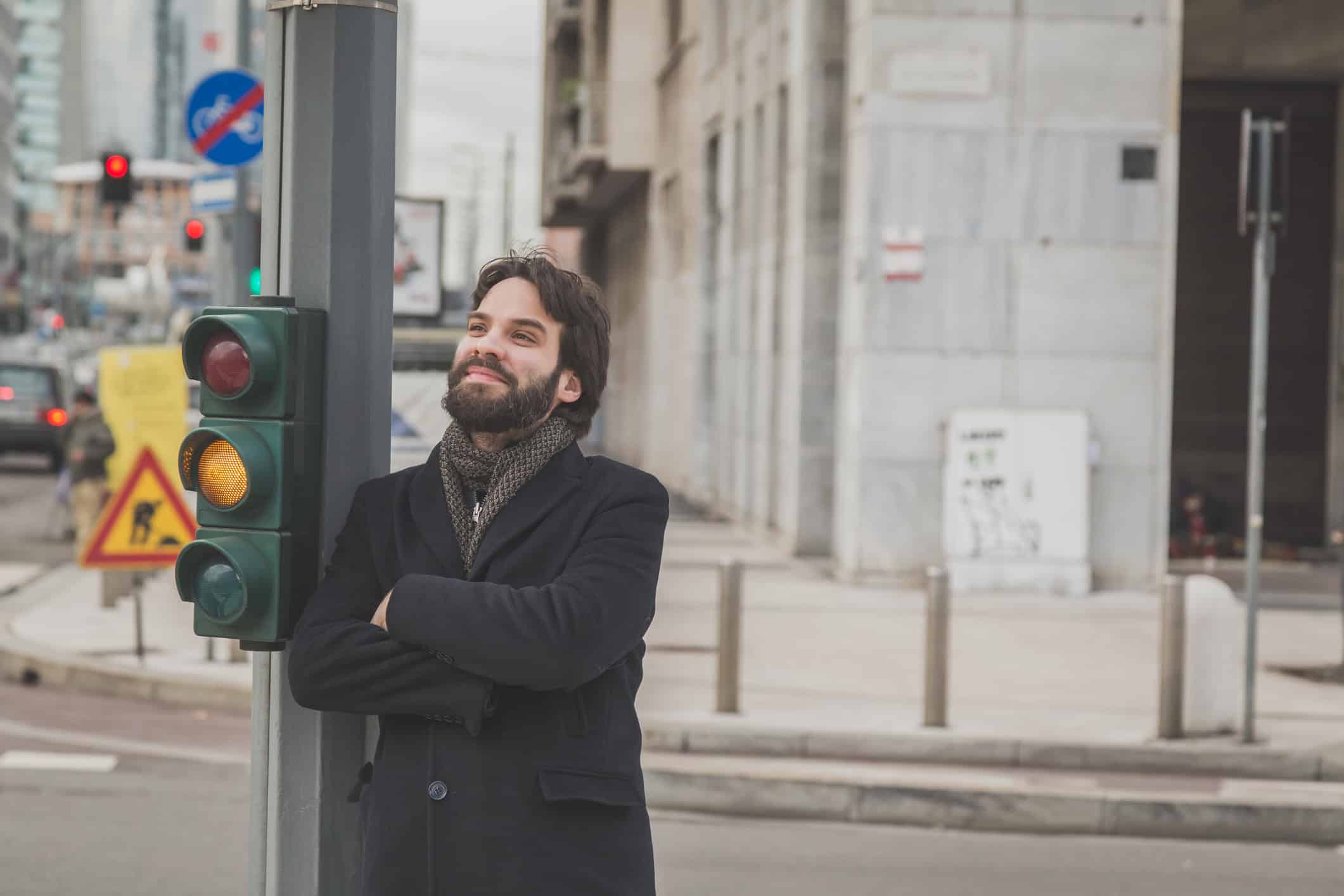 Man leaning on a street light post.