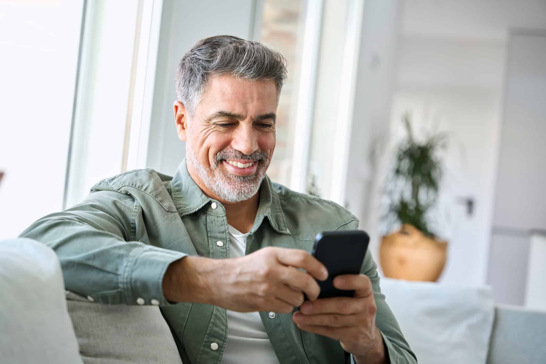 Man looking at his phone as he engages in online dating texting before meeting with a new relationship.