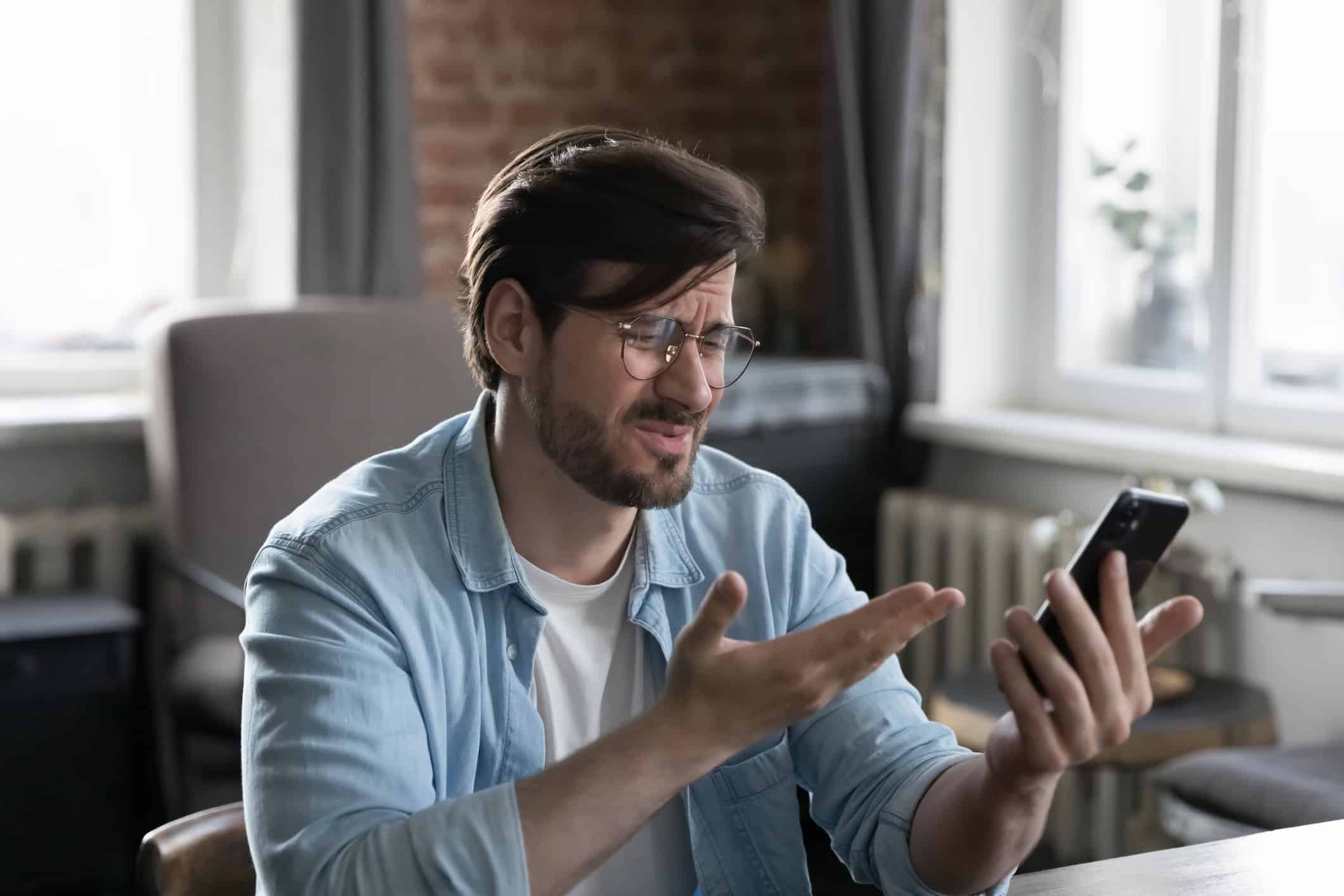Frustrated man looking at cellphone wondering "Is online dating a waste of time?"