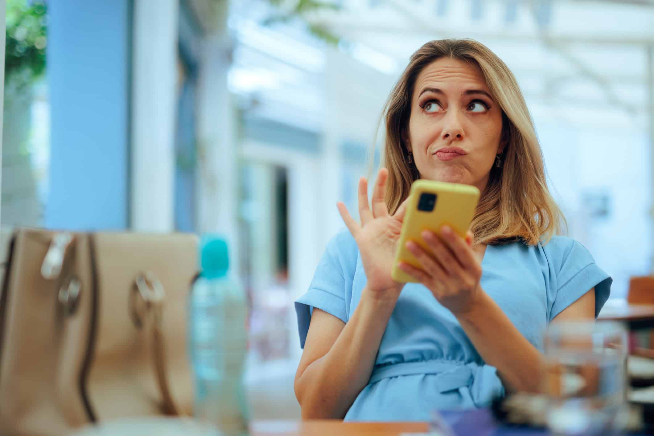A confused woman in blue is sitting alone and jumping to conclusions about a potential romantic partner she met online.