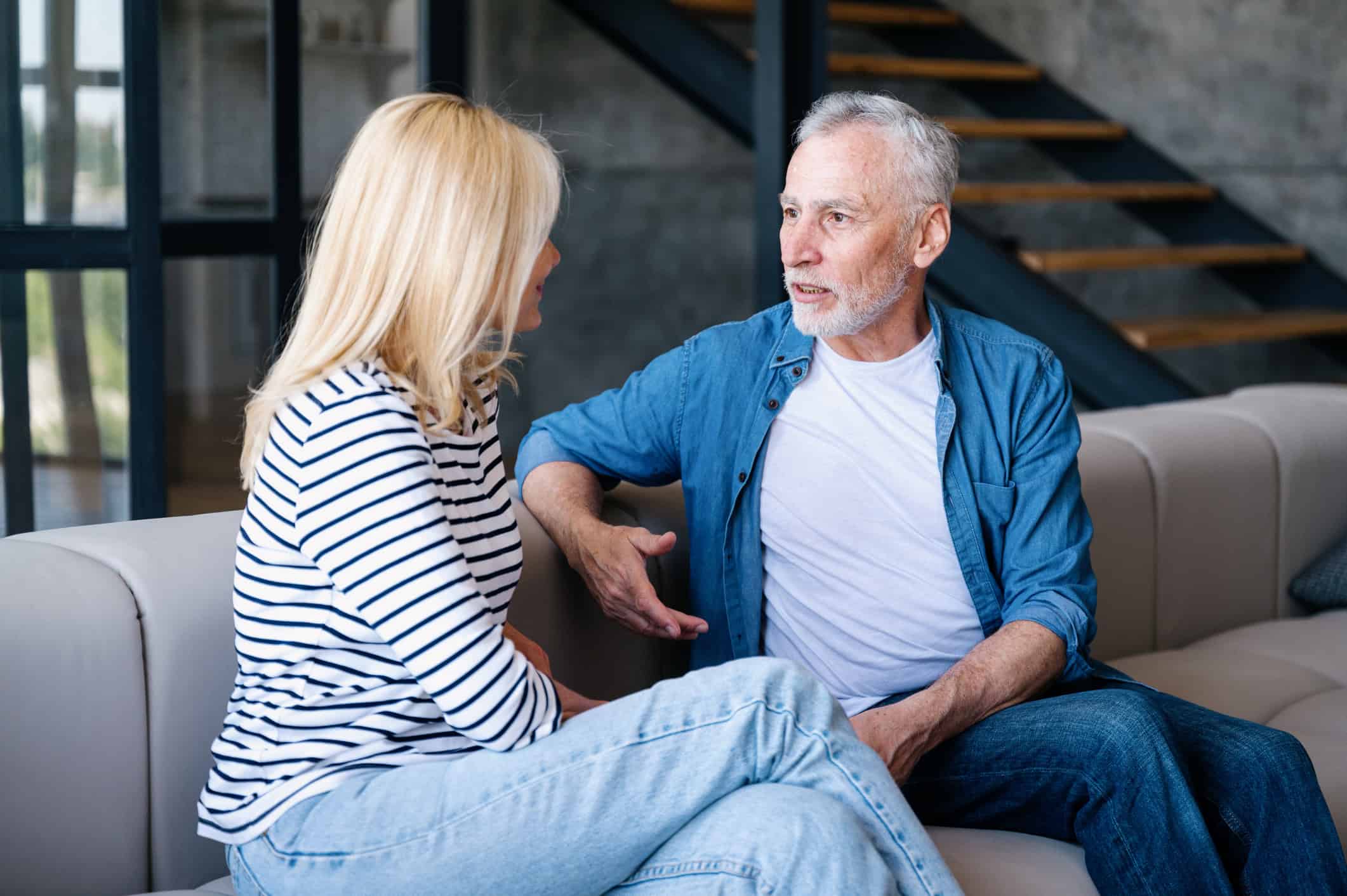 A mature man and woman sitting on a couch having serious dating conversations.