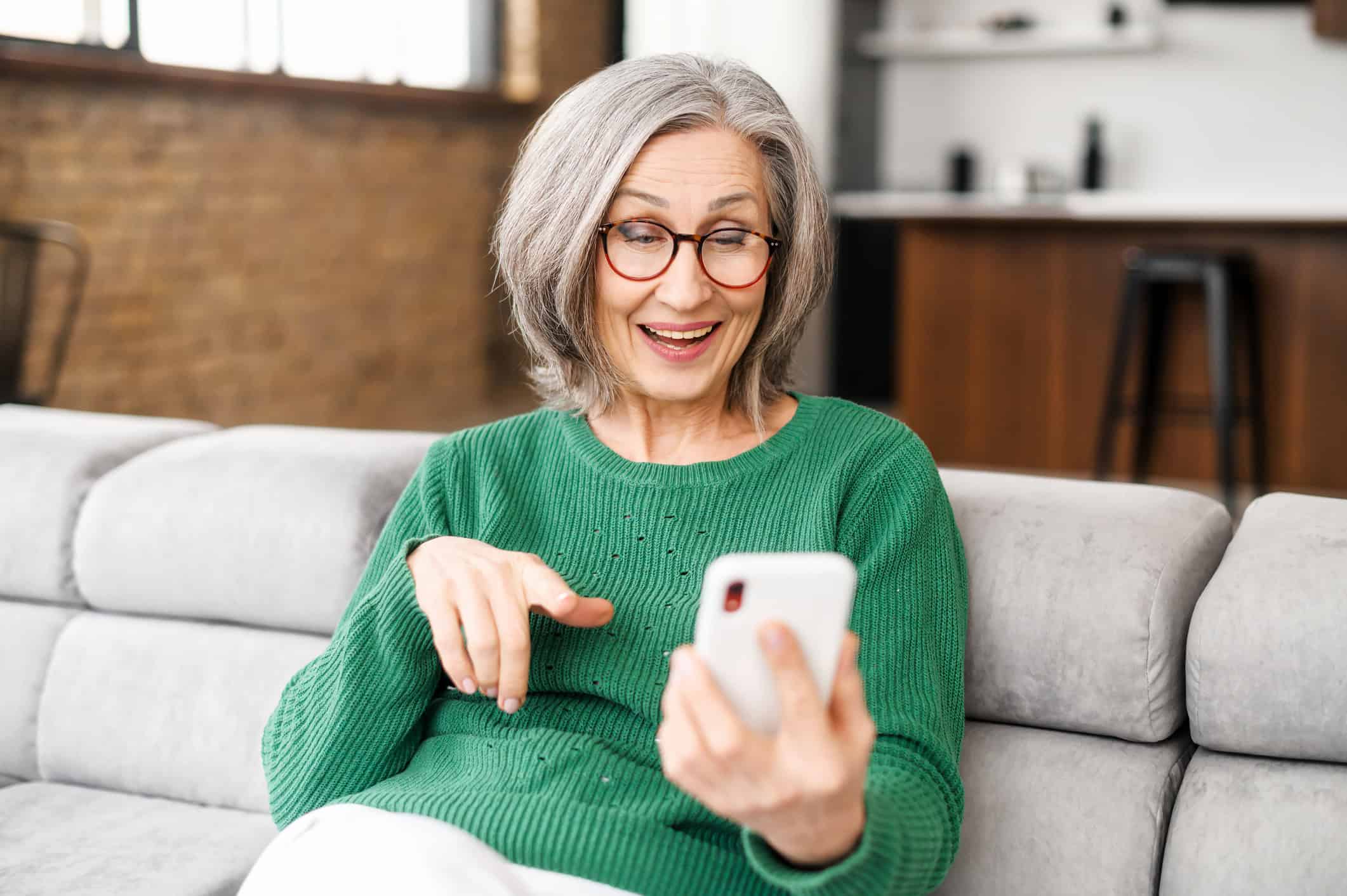 A mature woman sitting on her couch while learning how to get the best results when internet dating for over-60s adults.