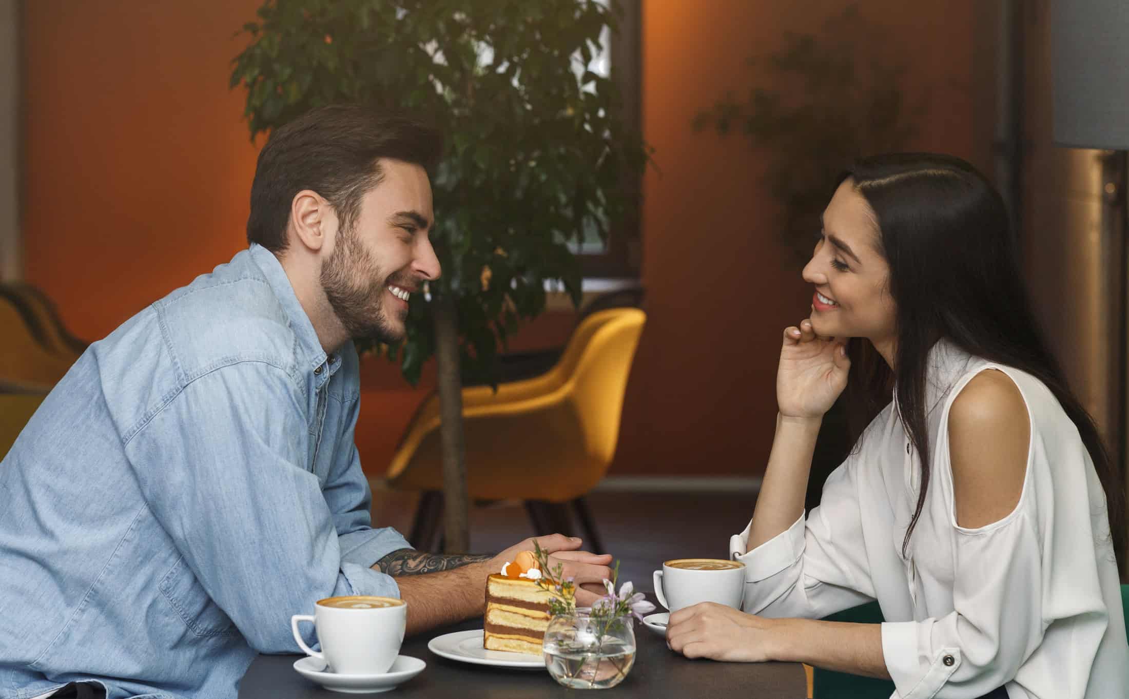 Single man and single woman over 35 sitting with coffee and dessert enjoying their date.