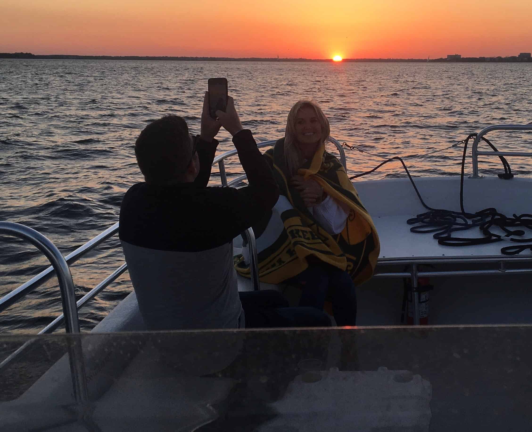 Woman getting her picture taken on the boat with the sunset behind her. Sunset booze cruise Charleston, SC