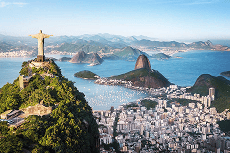 Vista panorâmica do Rio de Janeiro com o Cristo Redentor no Corcovado, o Pão de Açúcar, a Baía de Guanabara e a cidade ensolarada.