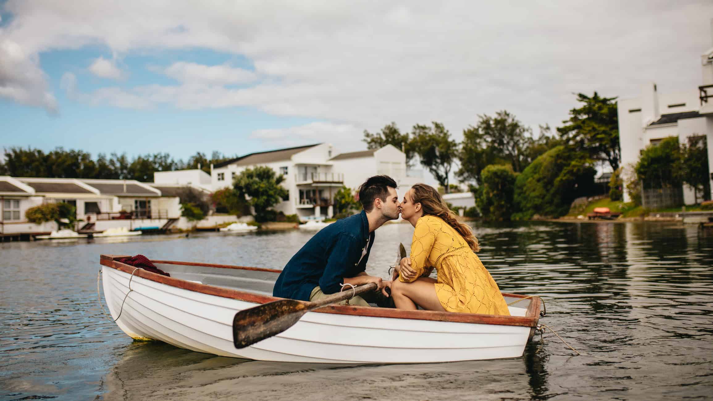 Couple in a rowboat gingerly leaning toward each other to kiss as they learn how to nurture a relationship.