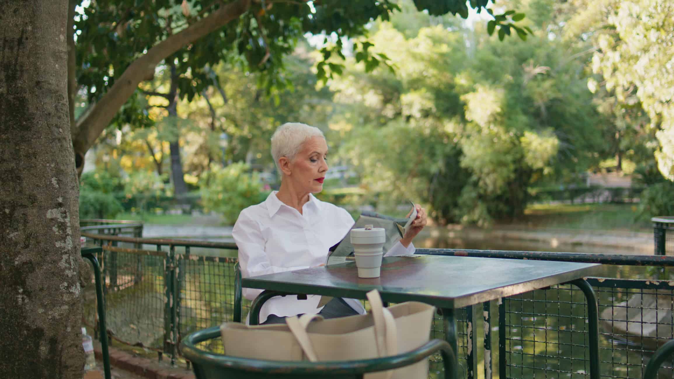 Mature woman sitting alone at an outdoor restaurant wondering why she's not dating and how to fix it.