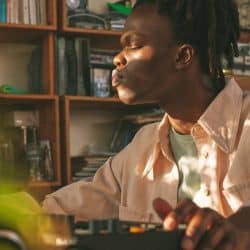 Professional music producer working in a cozy home studio with audio equipment and books, focused on beat making and music production, sunset light illuminating the scene, Creative industry, music technology, home studio setup.