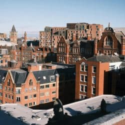 Colorful cityscape of historic and modern brick buildings in a vibrant urban setting with clear blue skies, showcasing architecture, skyline, and city life.
