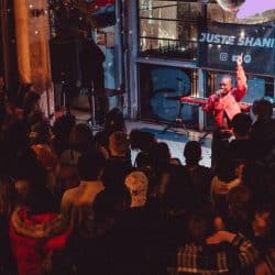 Live music performance at a bustling nightclub, featuring a singer with a microphone and a DJ playing electronic music, with a vibrant crowd enjoying the entertainment.