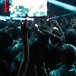 Vibrant concert crowd at a live music event with hands raised, colorful lights, and energetic atmosphere, capturing the essence of music festivals and nightlife entertainment.