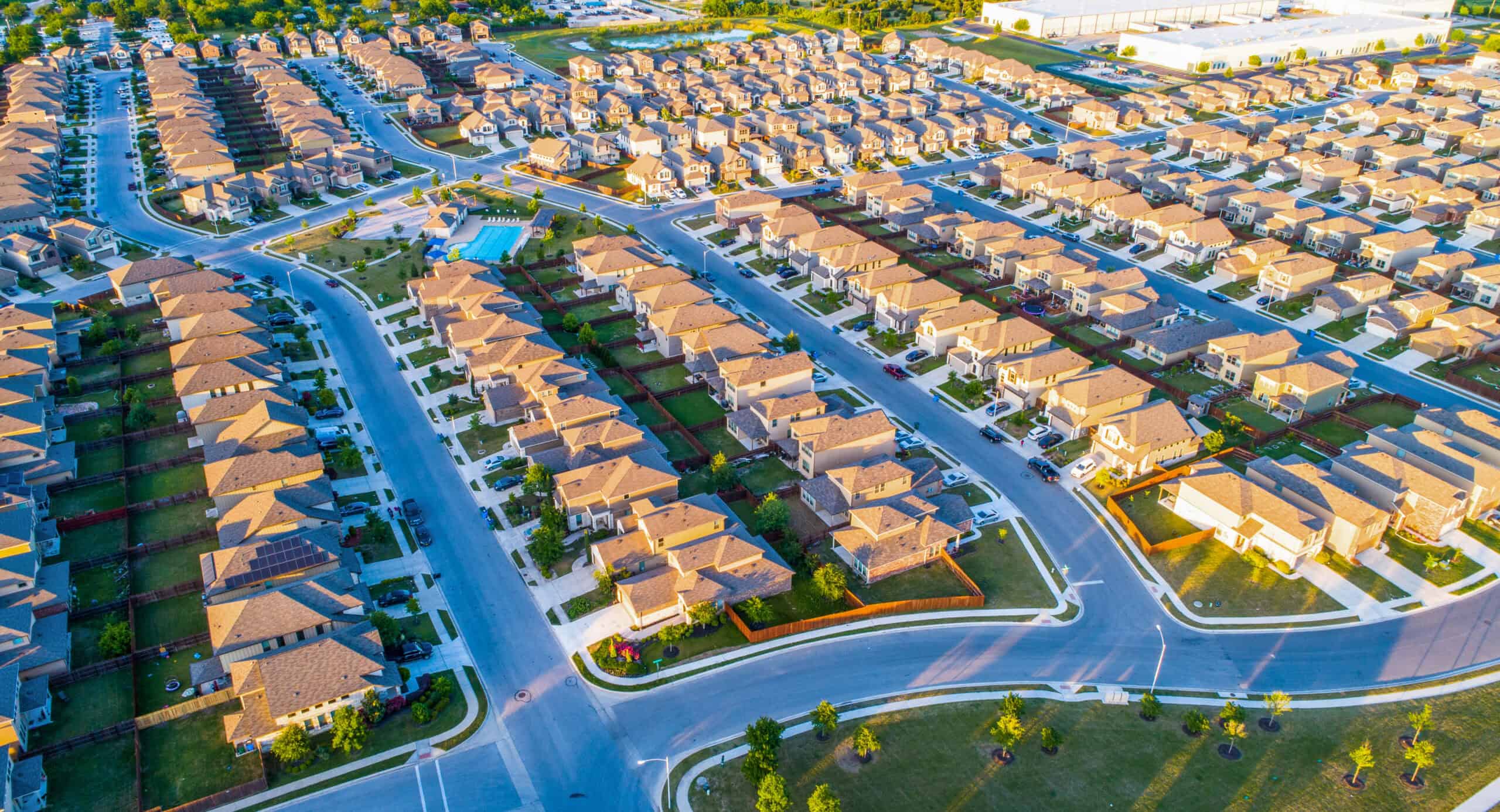 Aerial view of a large suburban residential development with uniform housing rows, streets, and a community pool — representing land development projects requiring environmental permitting, endangered species surveys, and wetland impact assessments by EDGE Engineering prior to construction.